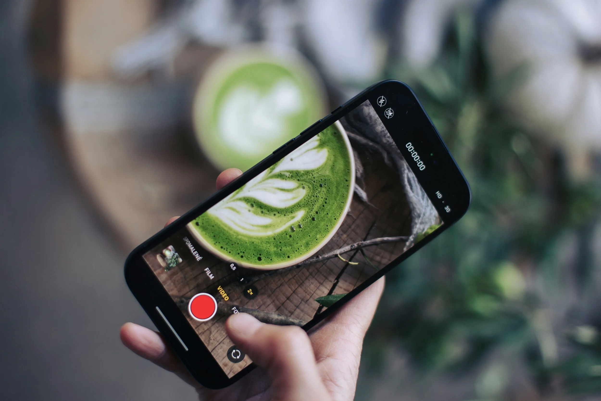 cup of matcha coffee being viewed through a phone camera