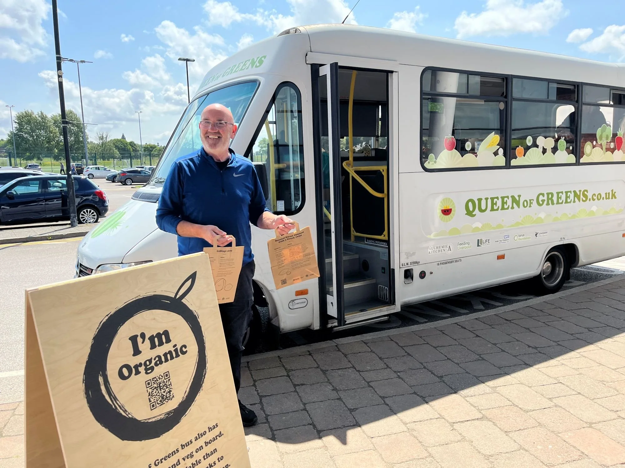 Man in front of a bus with Queen of Greens written on the side.
