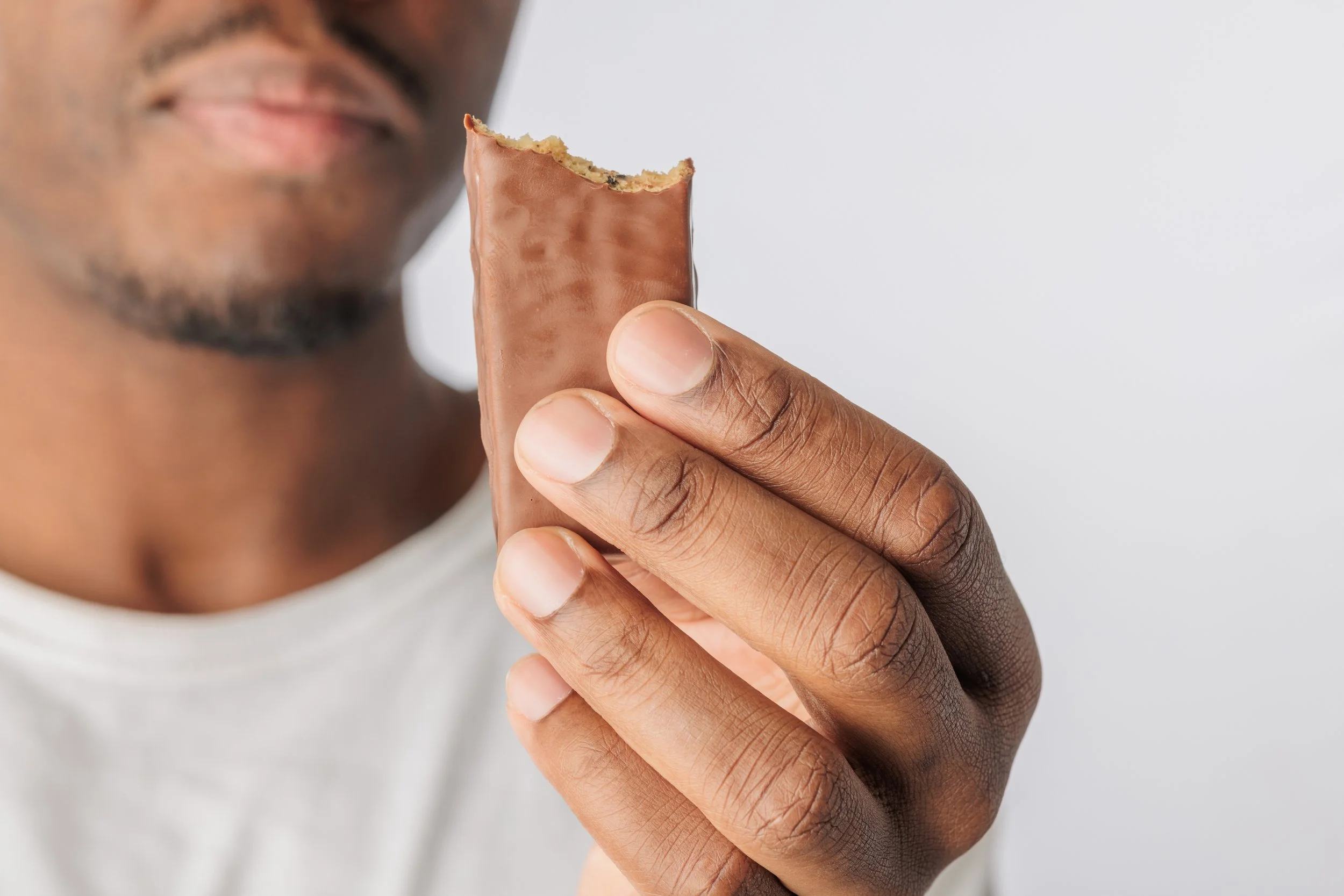 Close up of a hand holding a chocolate coated snack bar.