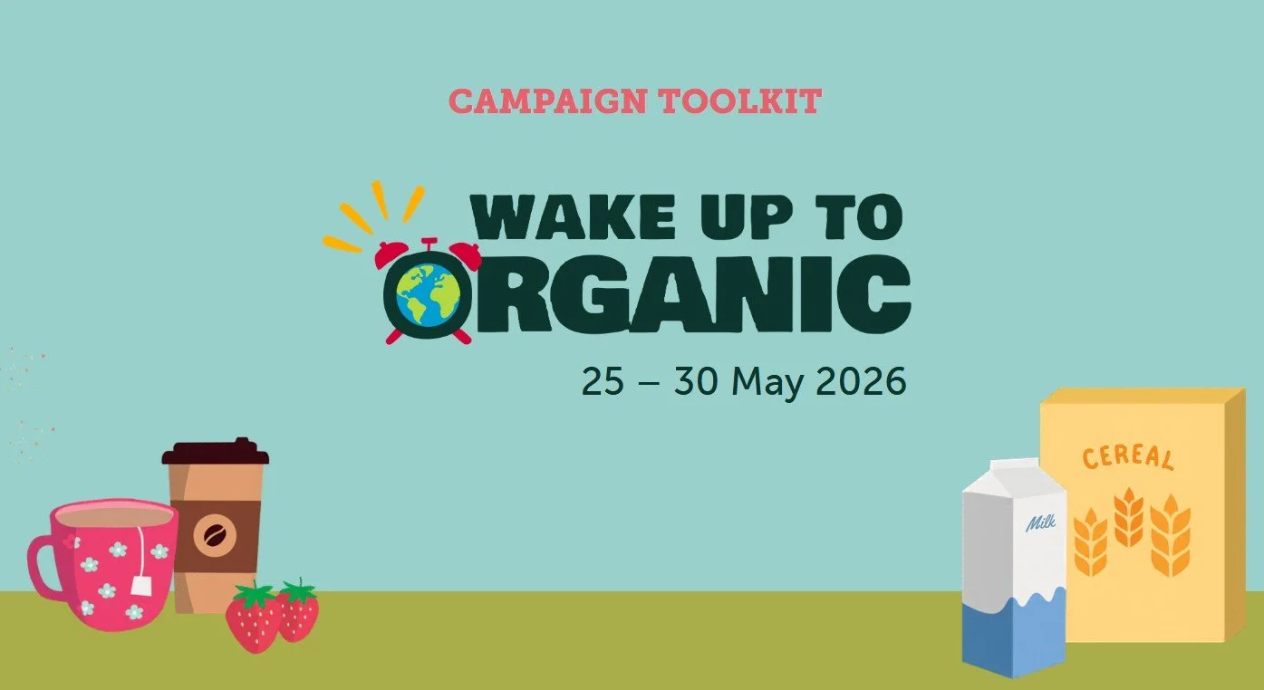 Wake Up to Organic campaign graphic for 25–30 May 2026, featuring an Earth alarm clock logo and illustrated breakfast items like coffee, strawberries, milk, and cereal.