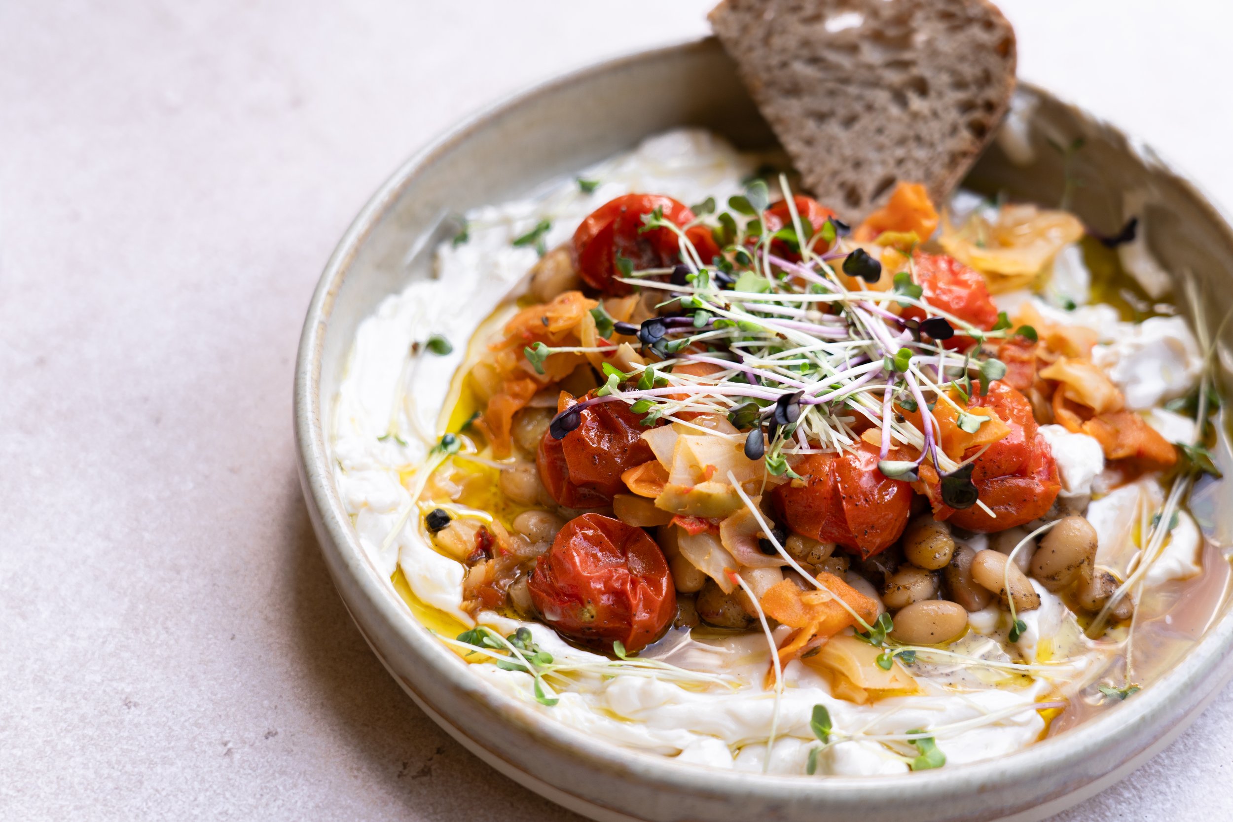 A creamy labneh topped with micrgreens and served with sourdough.