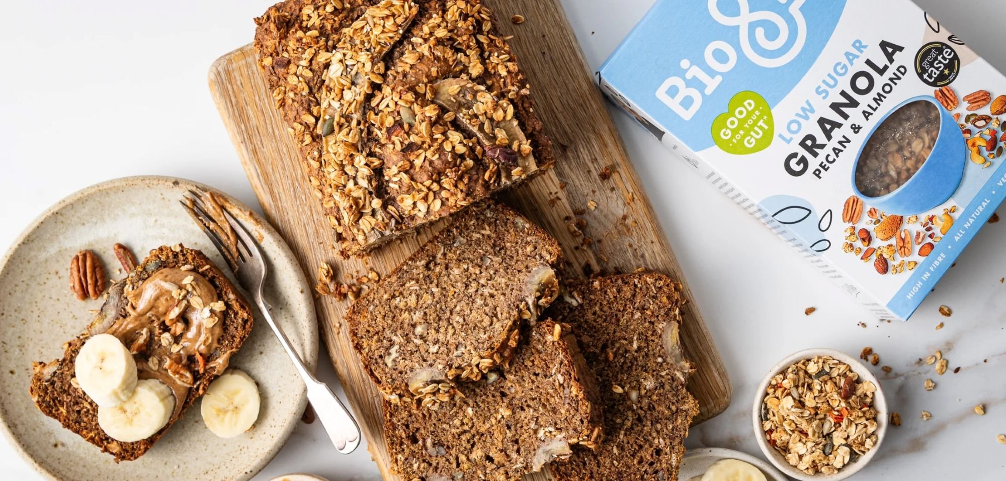Oat-topped banana bread slices with peanut butter and banana, served beside Bio&Me low sugar pecan and almond granola.