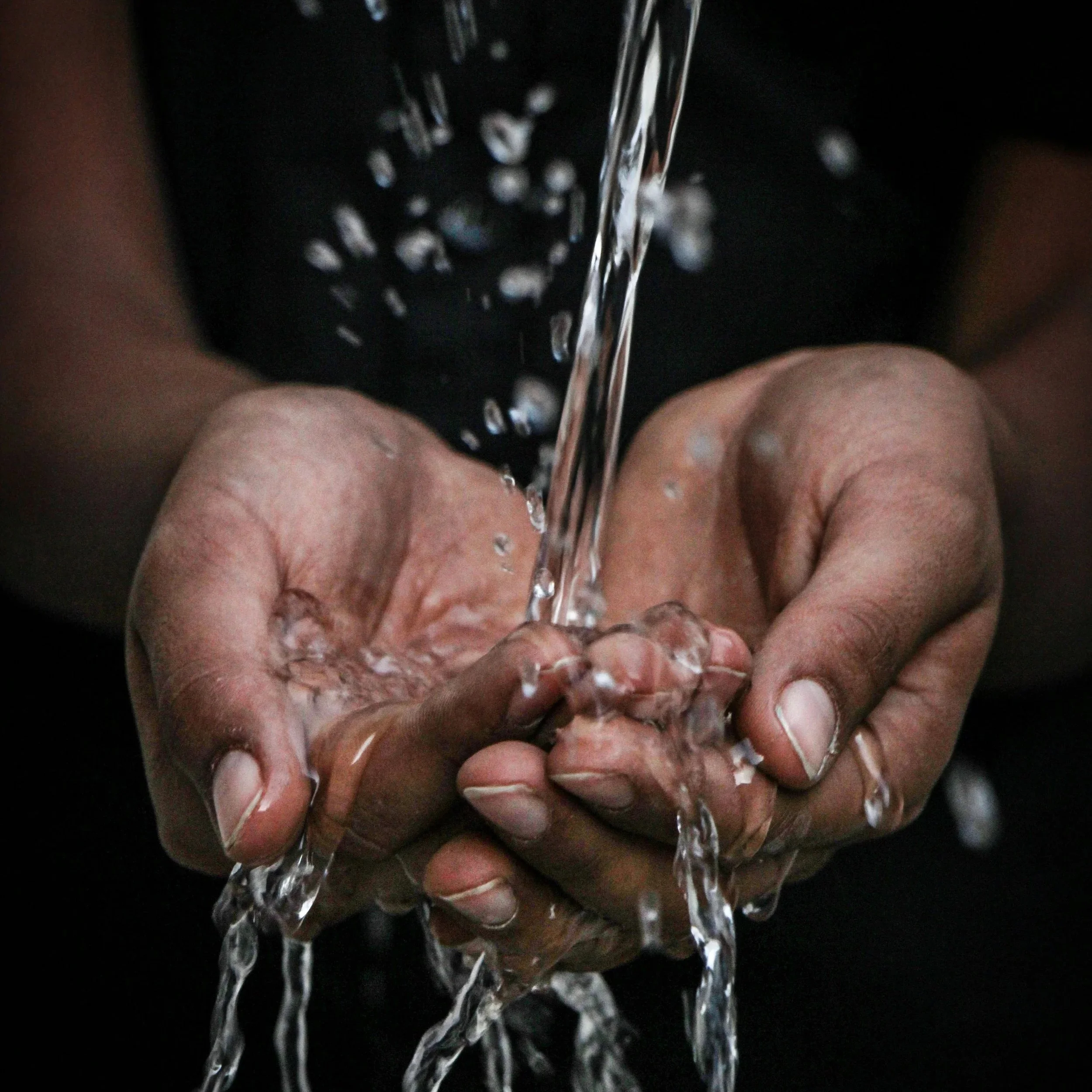 Water pours into a pair of cupped hands.