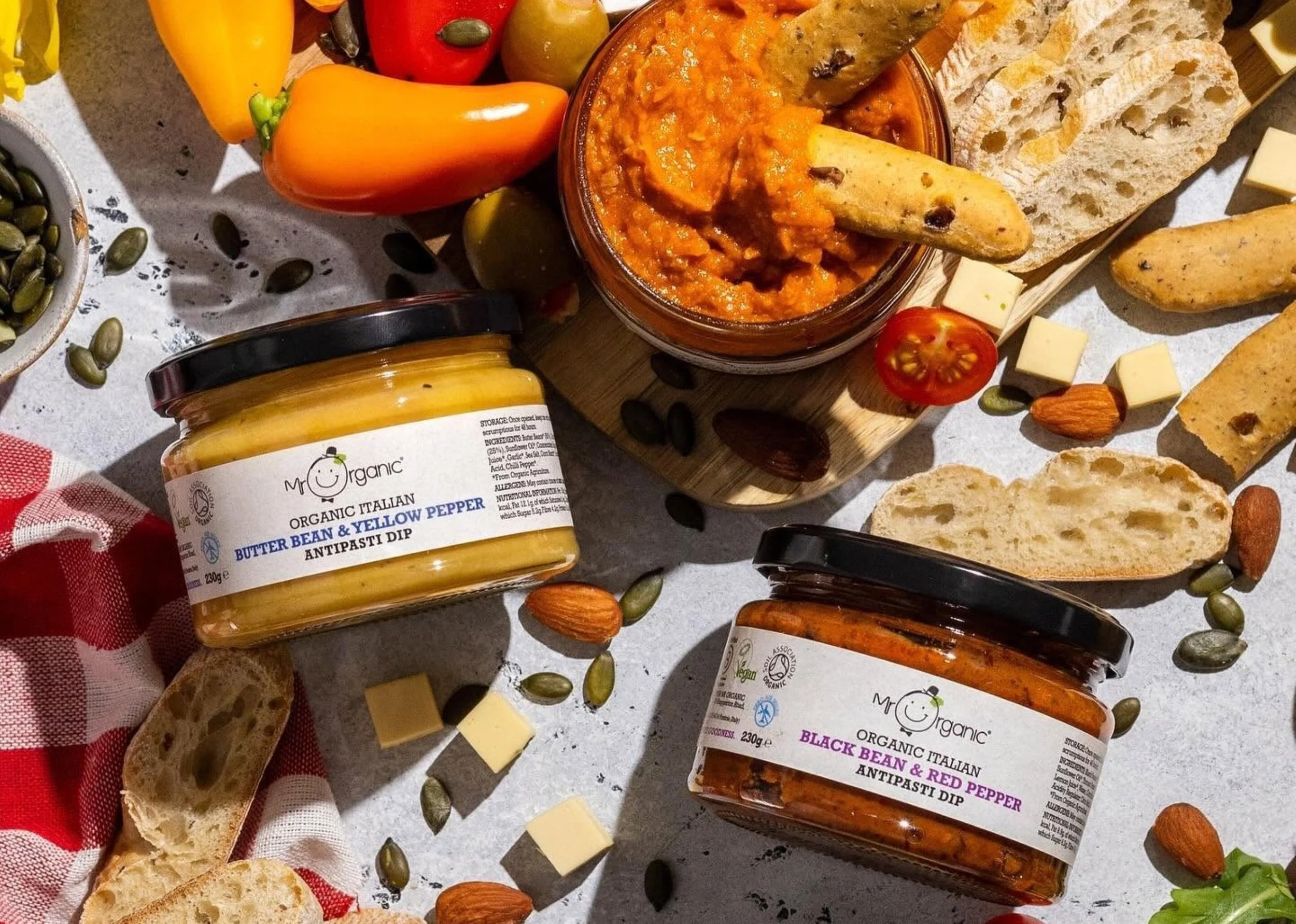 Mr Organic antipasti dips served with crusty bread, peppers, tomatoes, cheese cubes, almonds and seeds in an overhead food display.