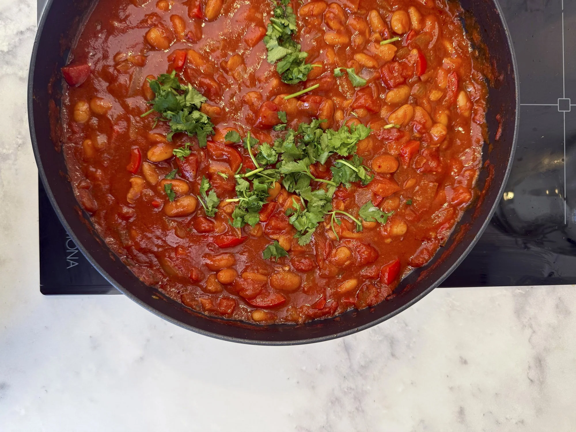 Bowl of bean and tomato soup topped with chopped parsley.