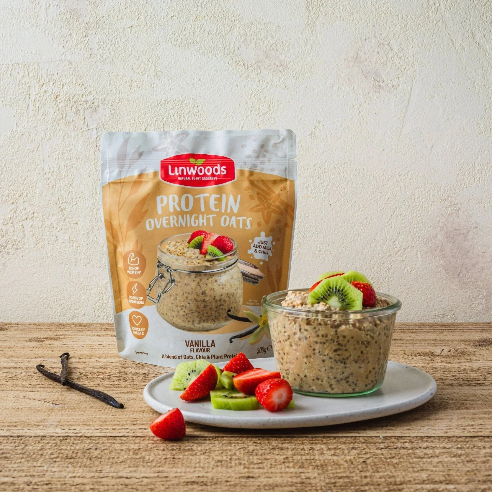 A kilner jar of overnight oats topped with fruit with a packet of Linwoods Protein Overnight Oats in the background