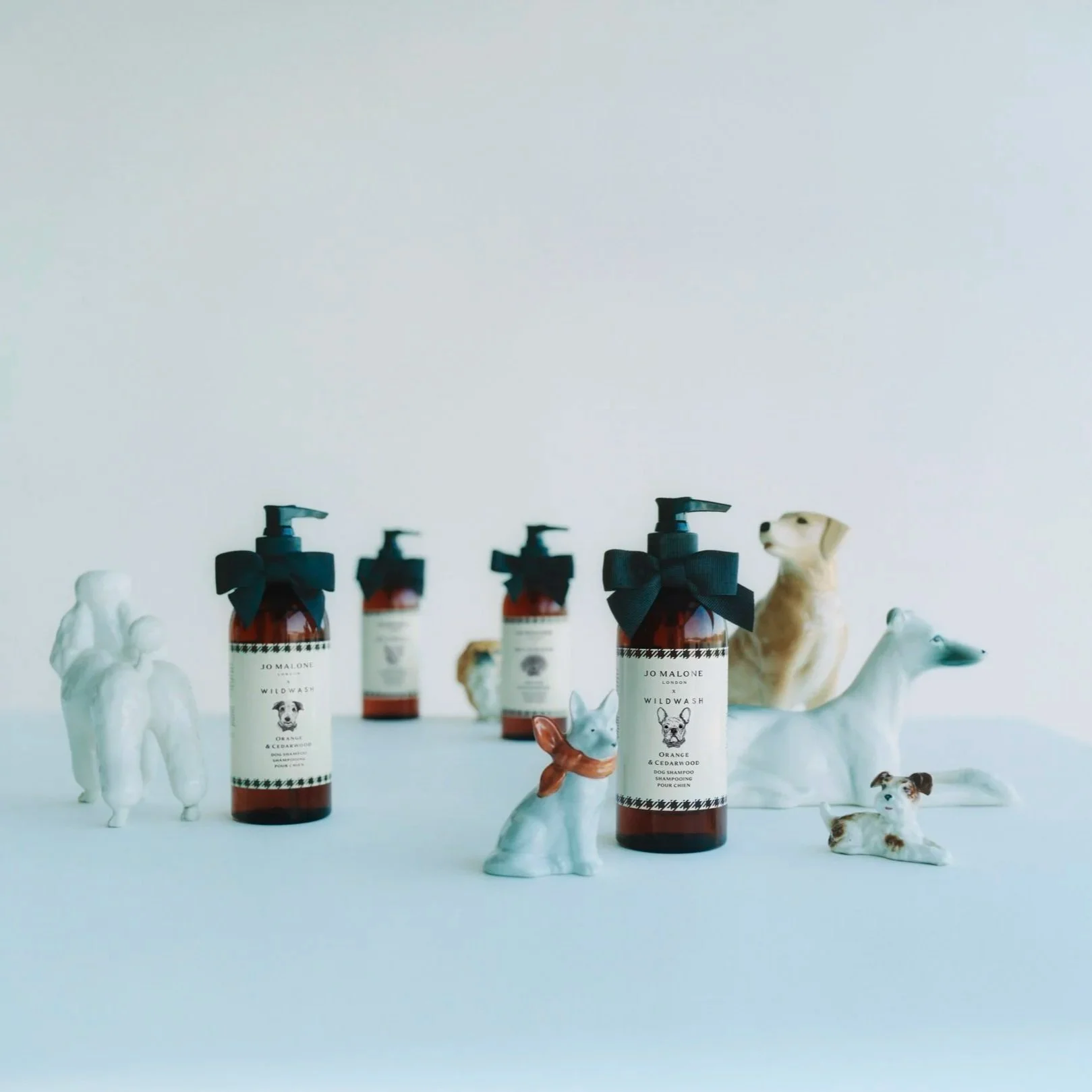 Jo Malone London and Wildwash Dog Shampoo bottles surrounded by ceramic dogs.