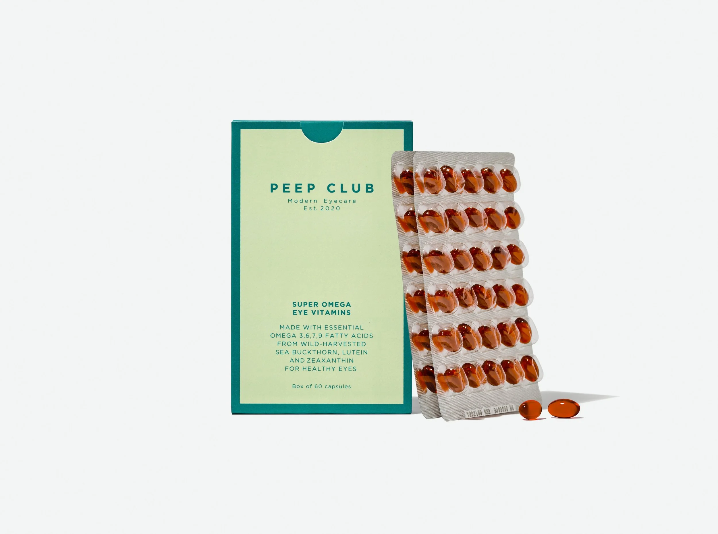 Light green box of Peep Club Super Omega Eye Vitamins alongside two blister packs of amber softgel capsules