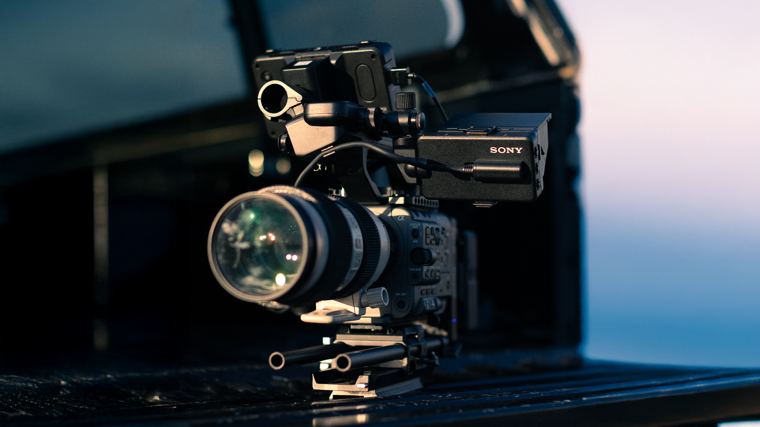 Professional video camera with Sony branding, mounted on a tripod or stabilizer, set outdoors during dusk or dawn.