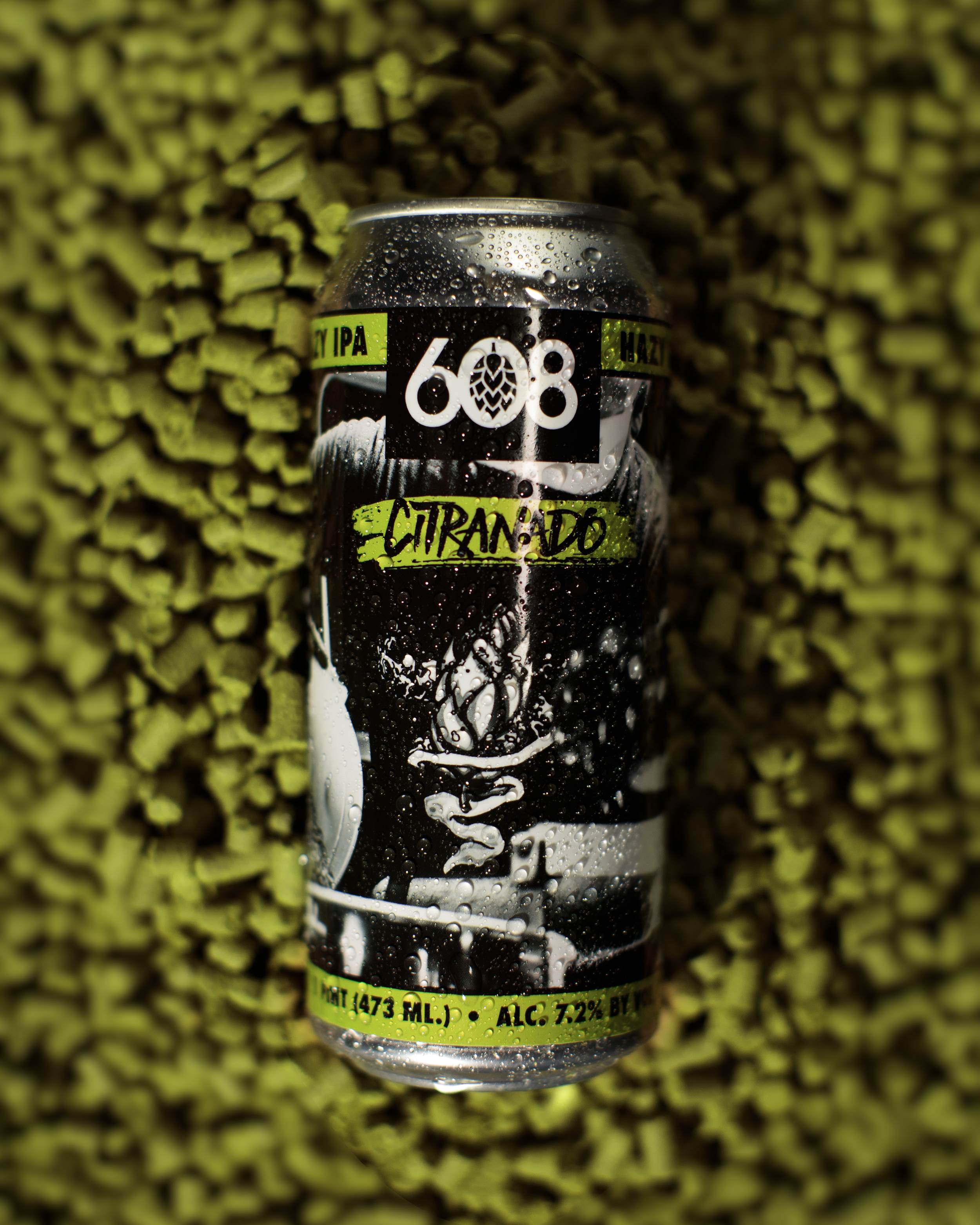 A can of Citranado beer with black, white, and neon green design, surrounded by green hop pellets.