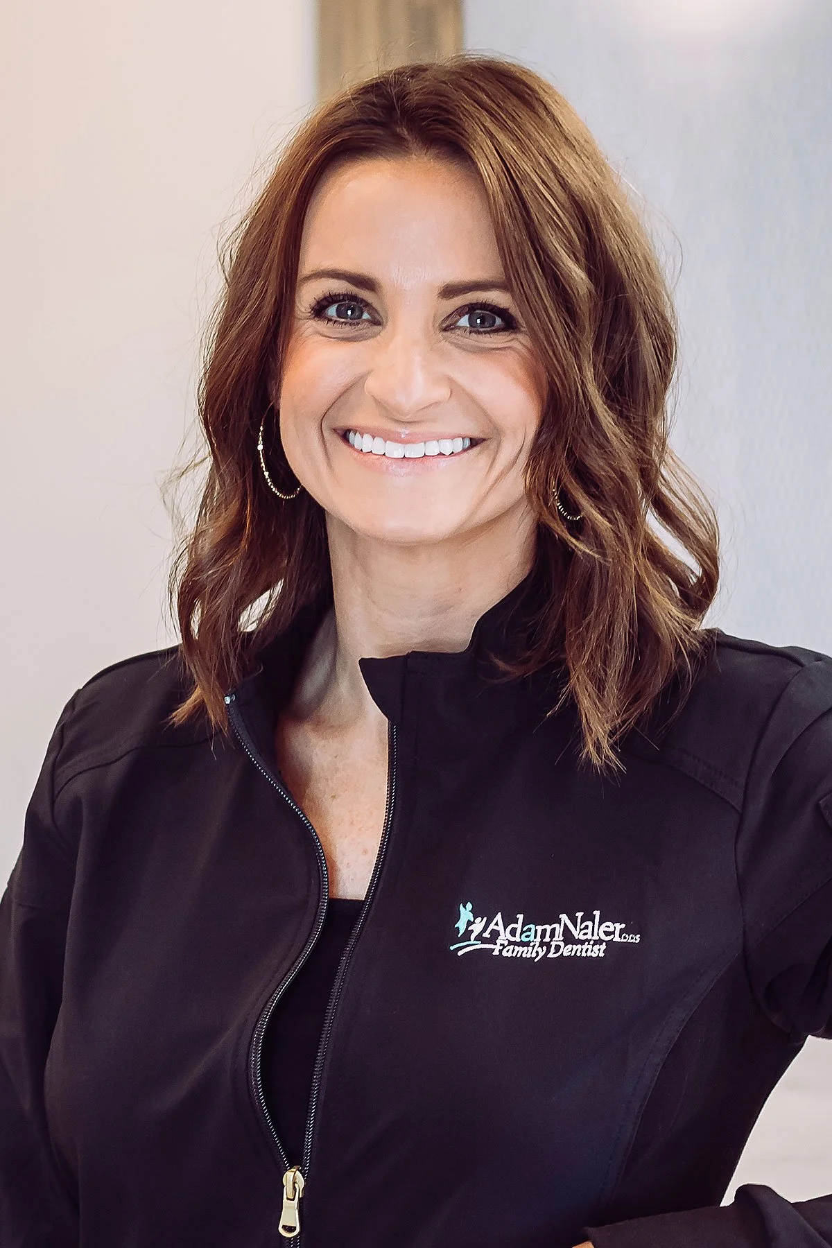 Hygienist in scrubs smiling at front desk