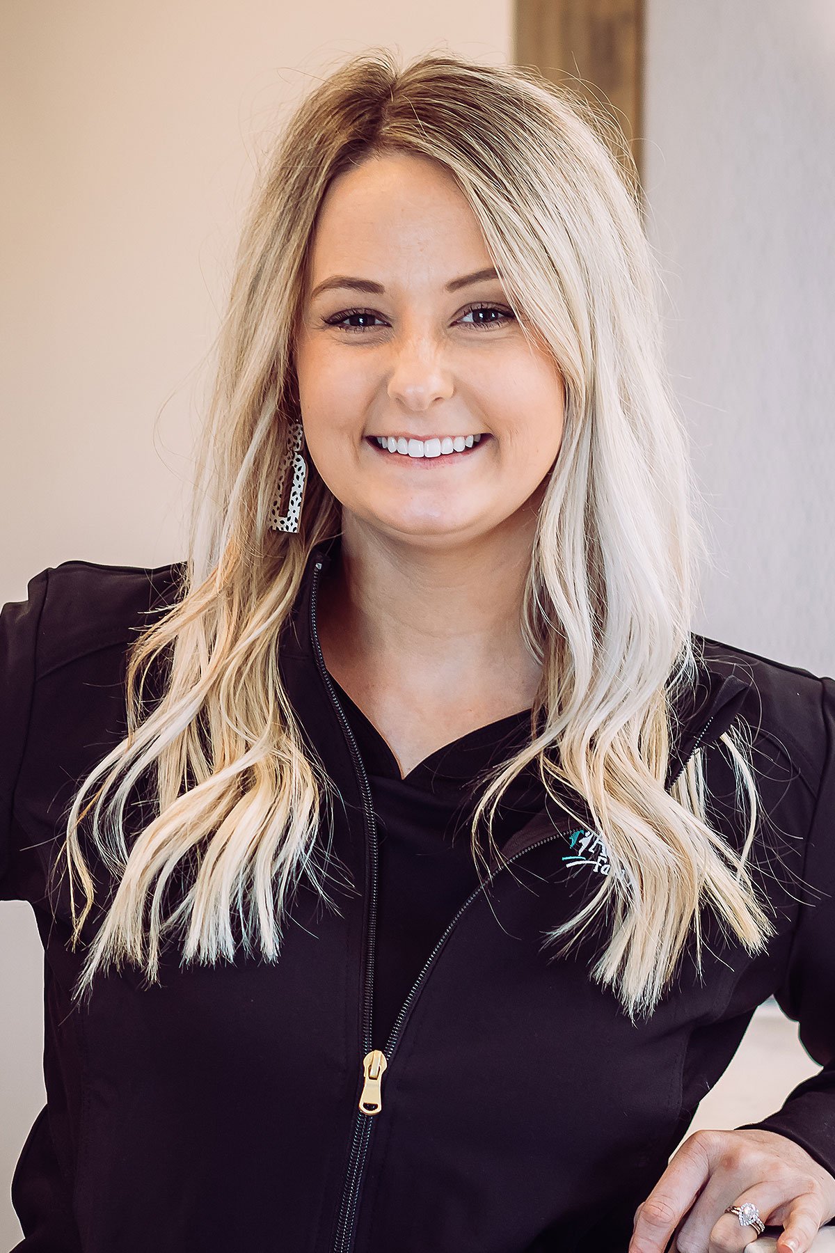Hygienist in scrubs smiling at front desk
