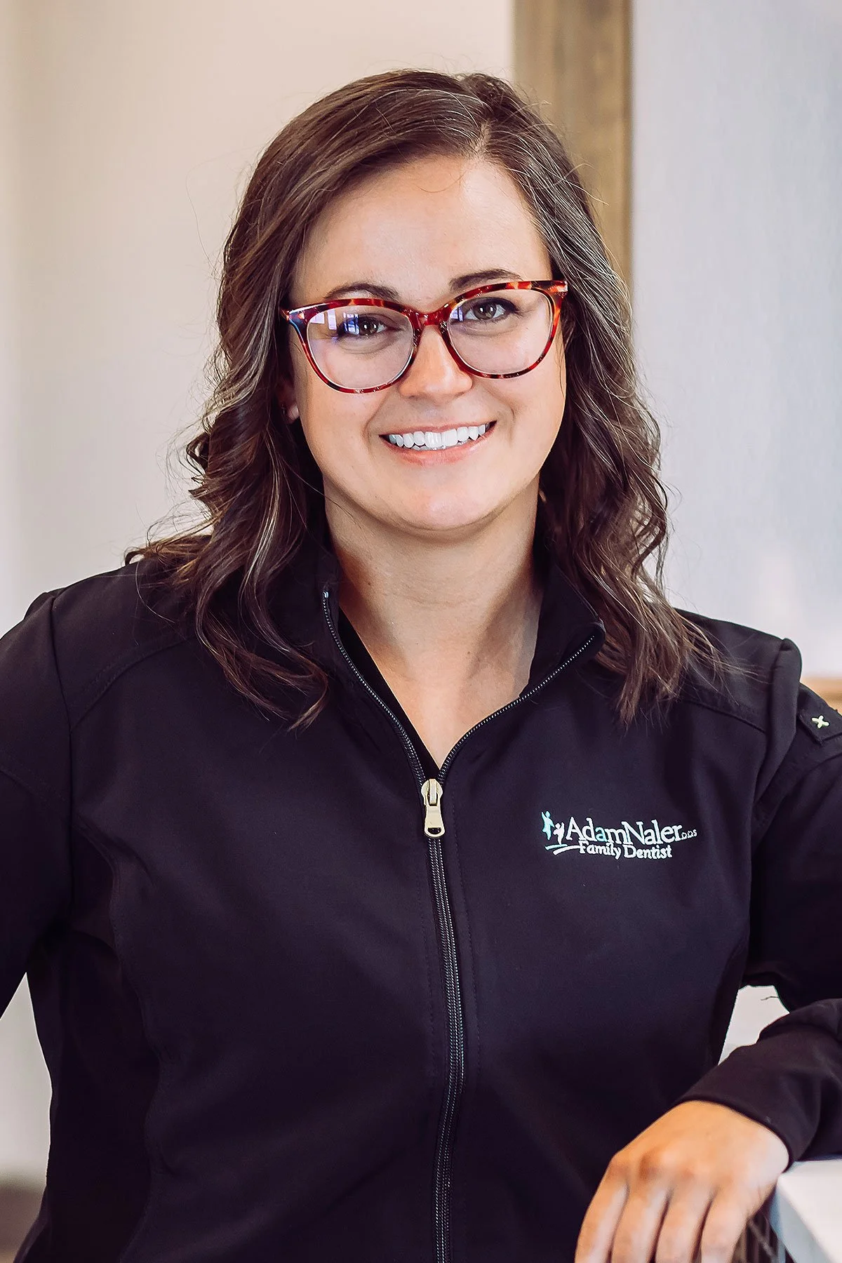 Hygienist in scrubs smiling at front desk