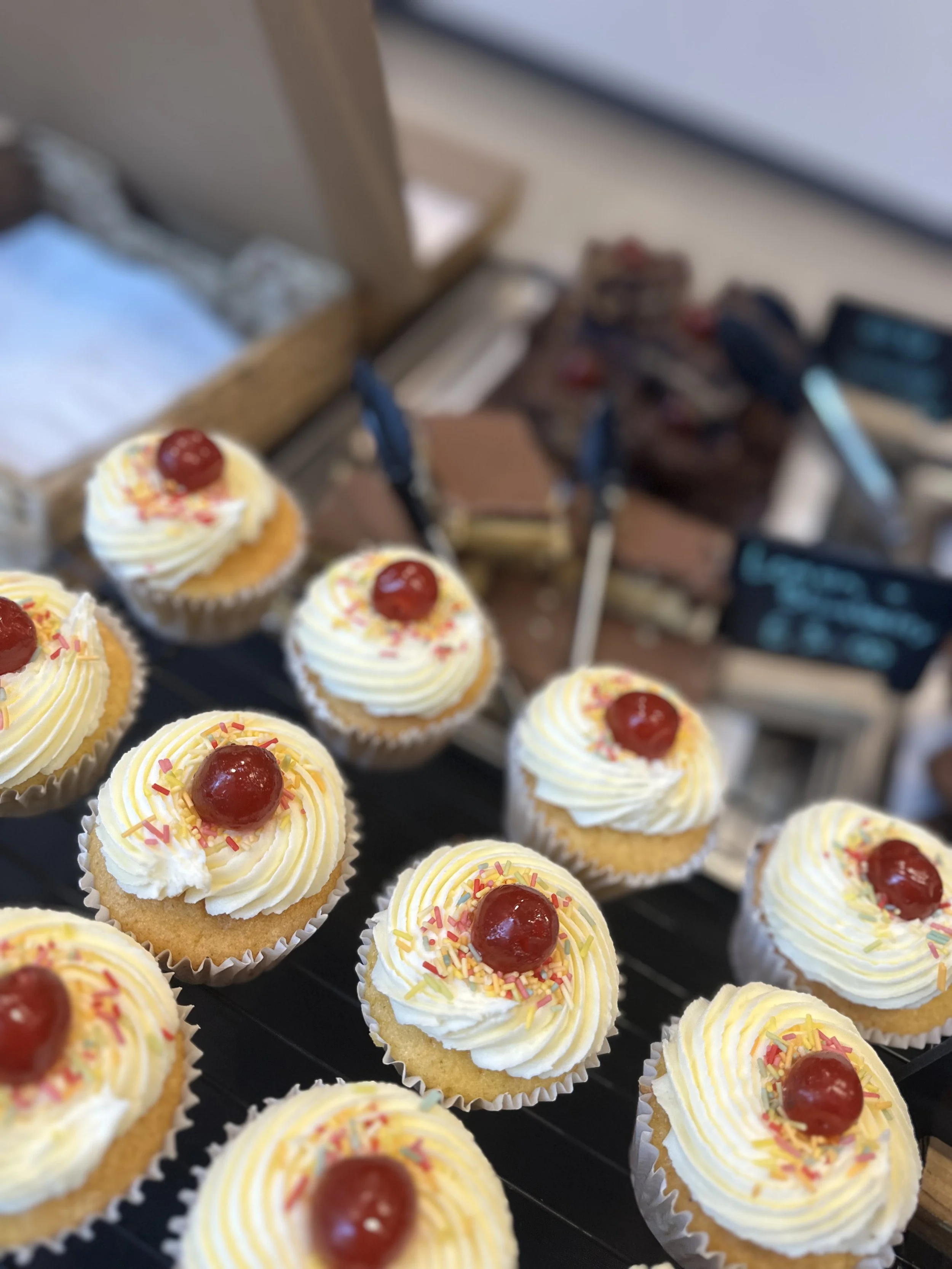 Freshly baked cupcakes with buttercream, sprinkles and cherries for wholesale customers