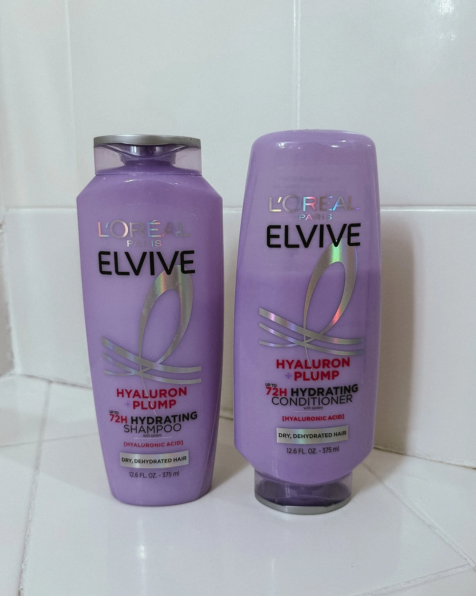 Woman's shower and post-shower body care routine featuring Tree Hut Tropic Glow, Naturium body wash, Saltair body oil, eos Vanilla Cashmere lotion, and Ouai leave-in conditioner.
