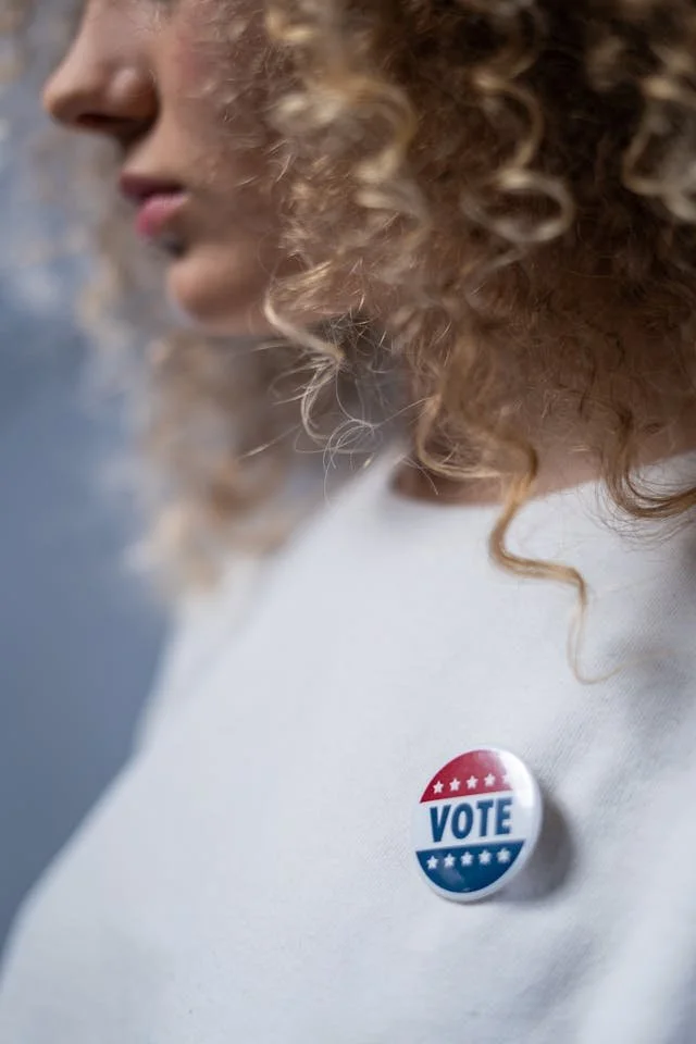 woman with curly hair and I voted sticker