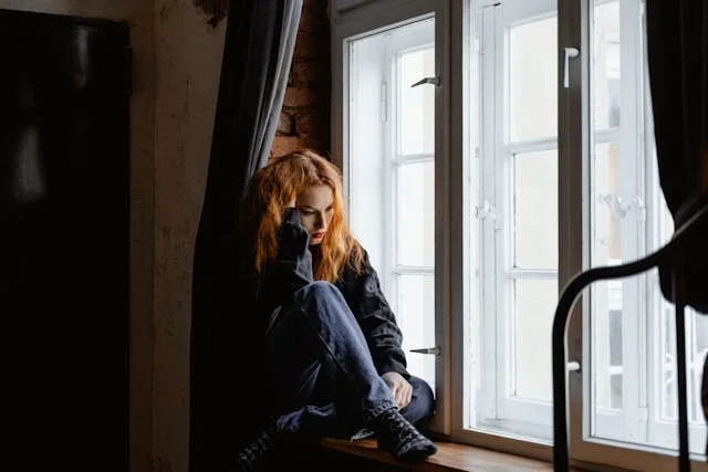 Woman in Black Leather Jacket Sitting on Brown Wooden Floor