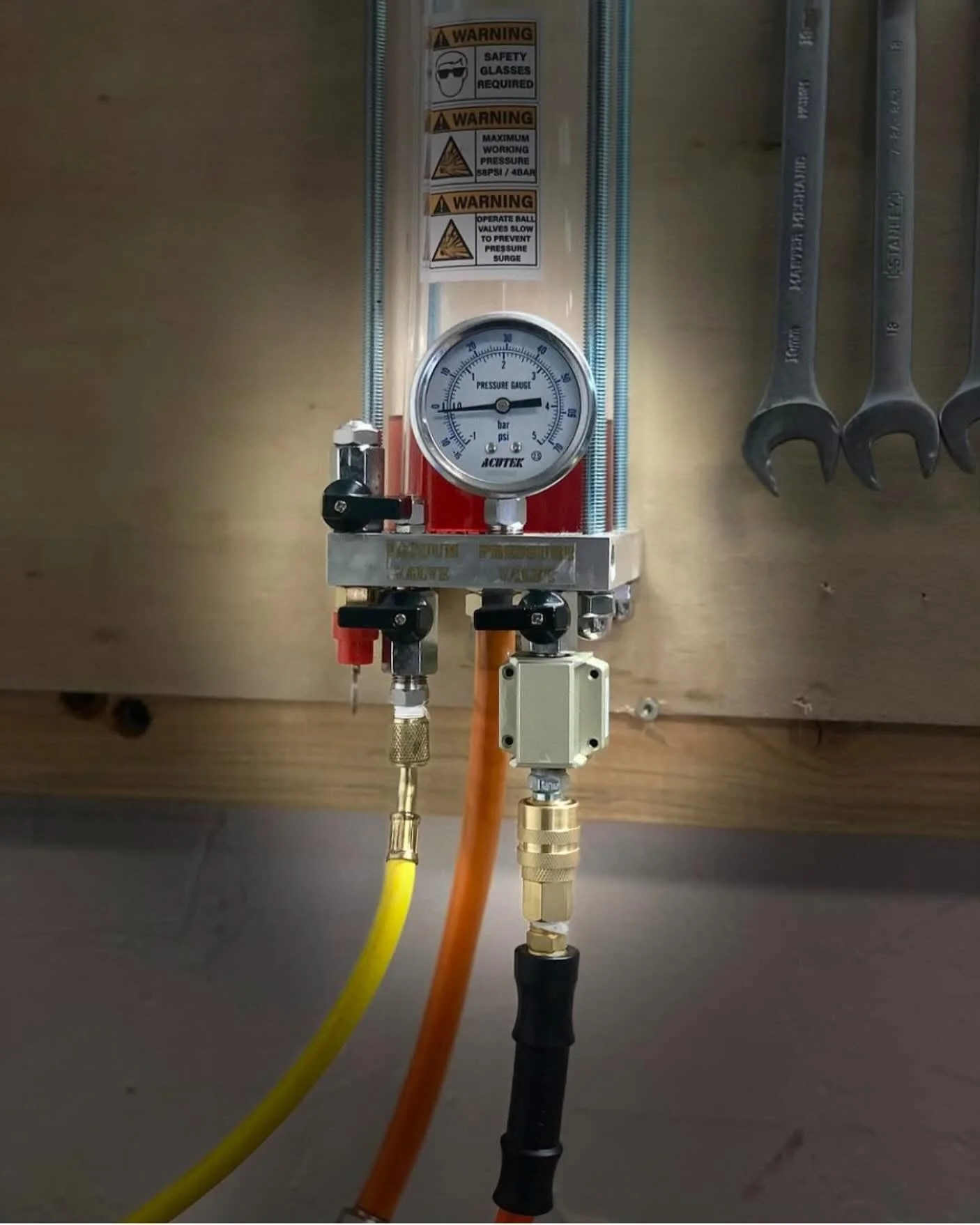 Close-up of a bicycle's rear suspension system, featuring a Fox shock absorber, set in a workshop with tools and other bikes visible in the background.