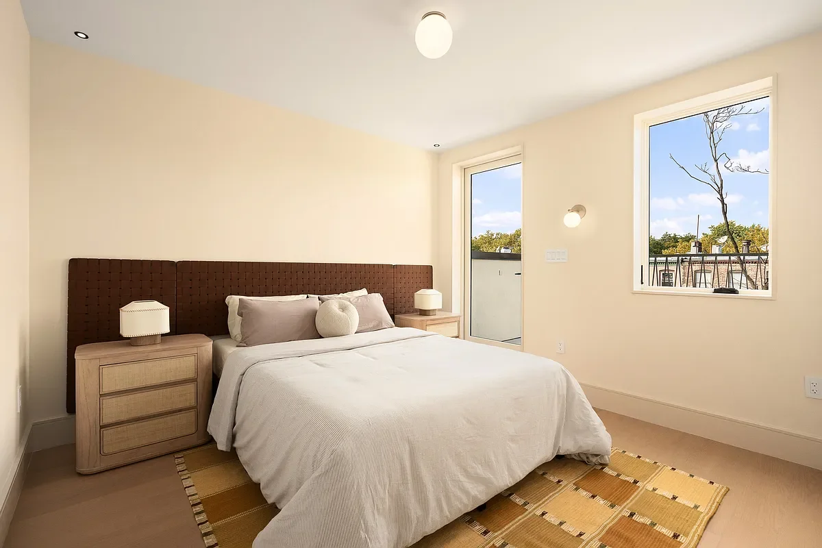 A bedroom with a bed, two nightstands with lamps, a window, and a door leading to a balcony or outside area.