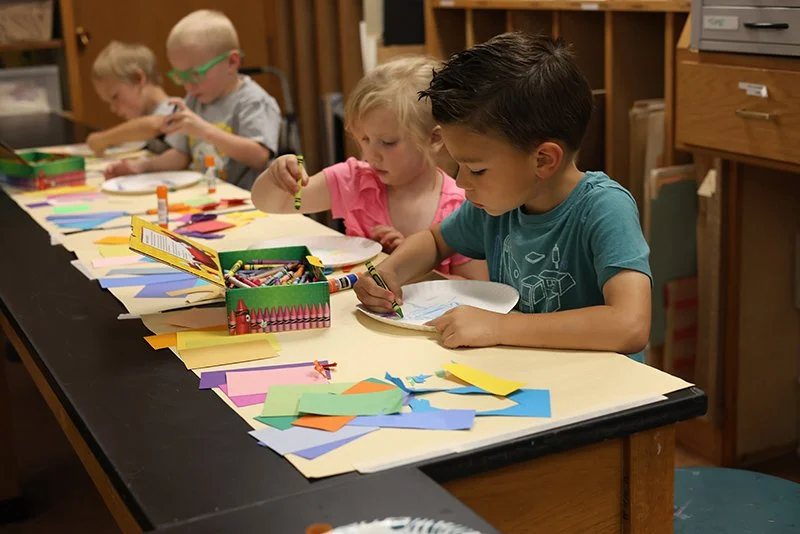 Four children making art at a classroom table