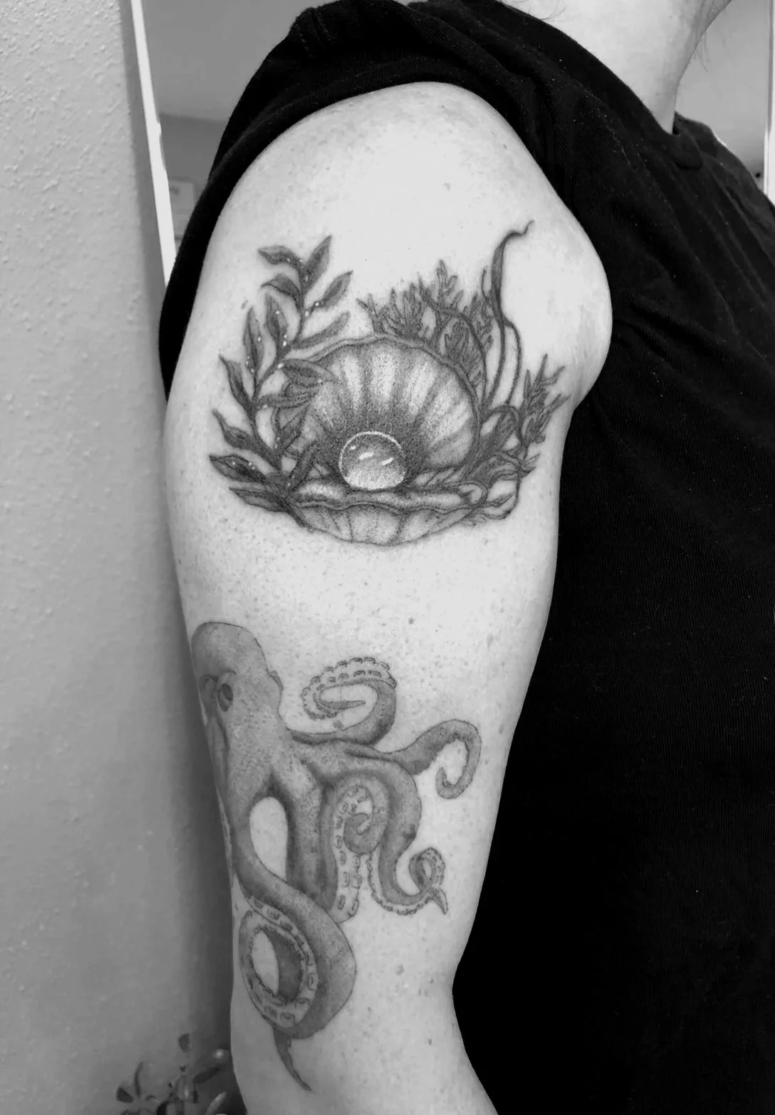 Tattoo of a snail and an octopus on a person's upper arm.