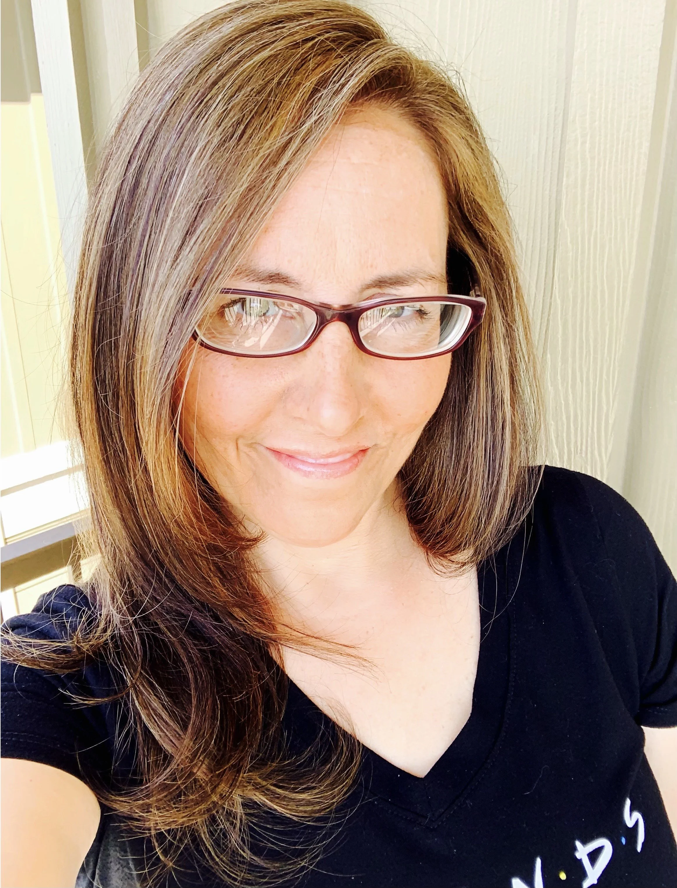 Woman with glasses, long hair, wearing a black shirt.