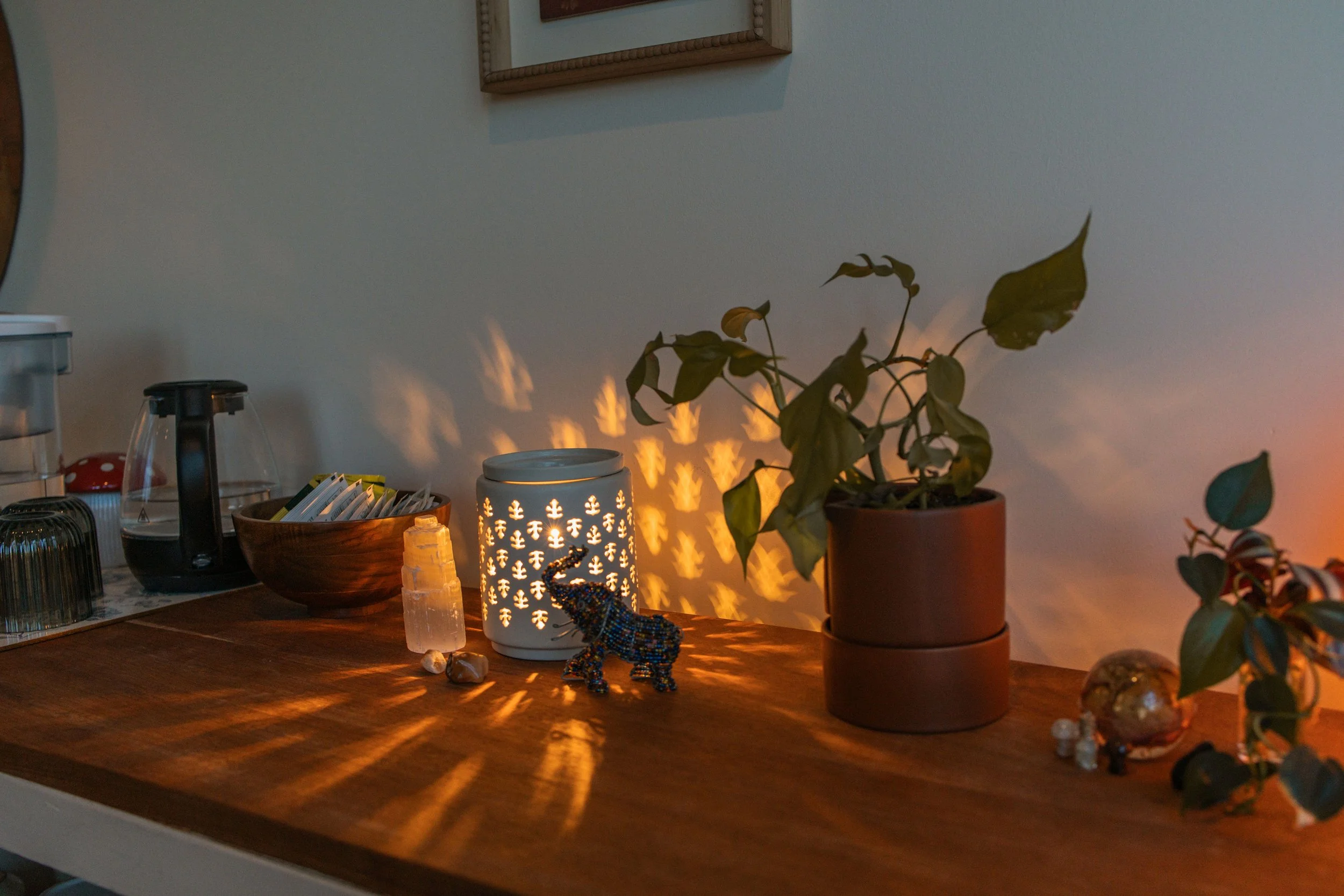 Decorative tabletop with a lit candle holder, potted plants, and small decorative items, creating a cozy ambiance.