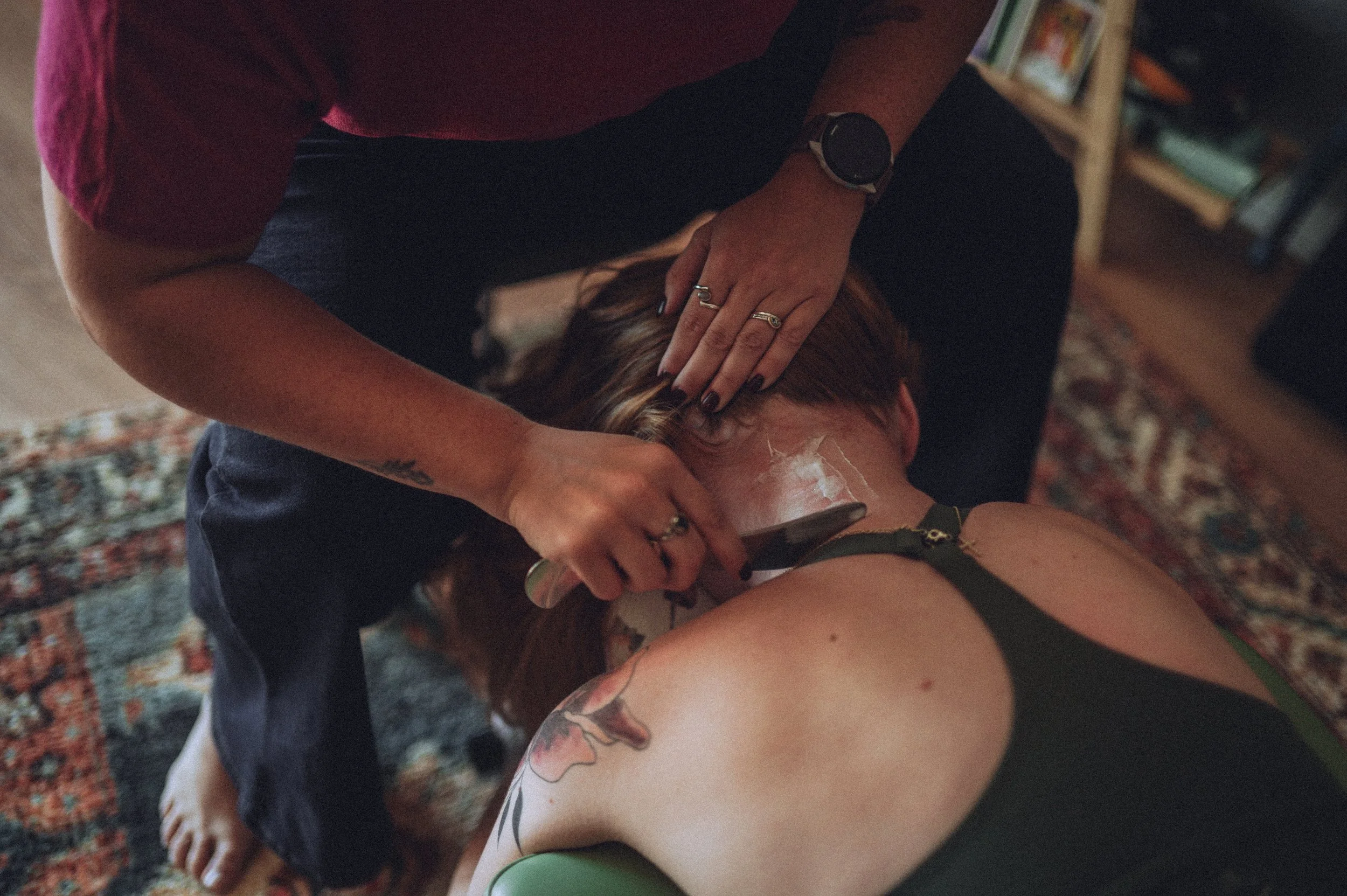 Person receiving a head massage or hair treatment from another individual.