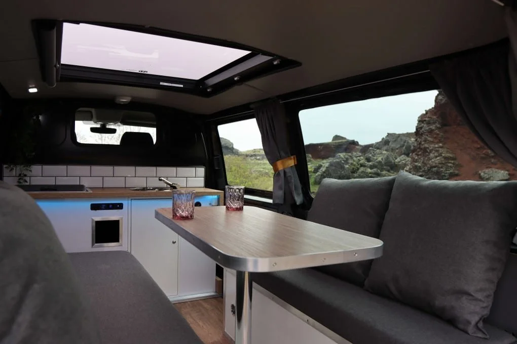 Inside a CozyCampers campervan in Iceland with bed, stove, and sink