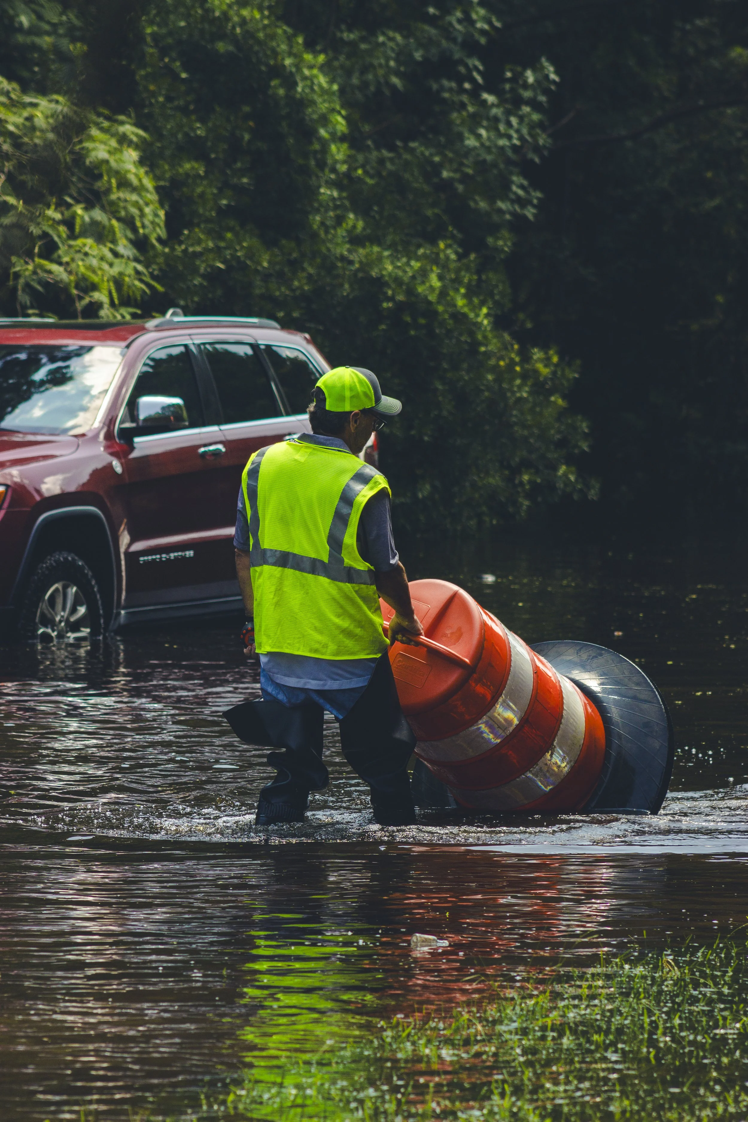 A Savannah city worker dragging traffic cones in the flooded water