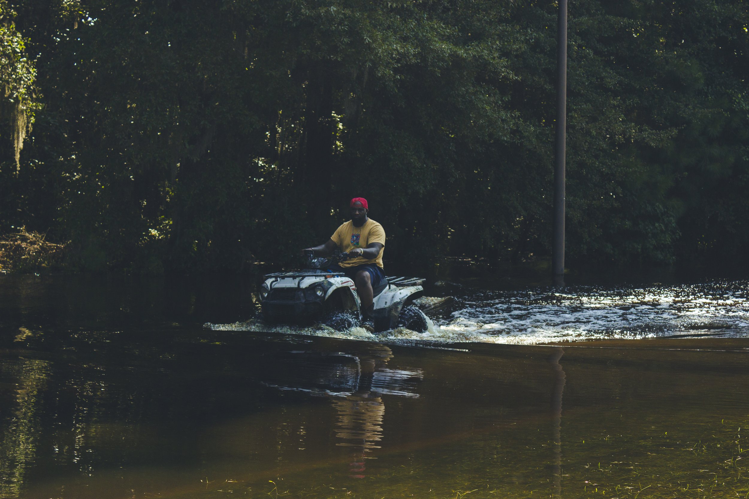 A resident on an ATV plowing through the water