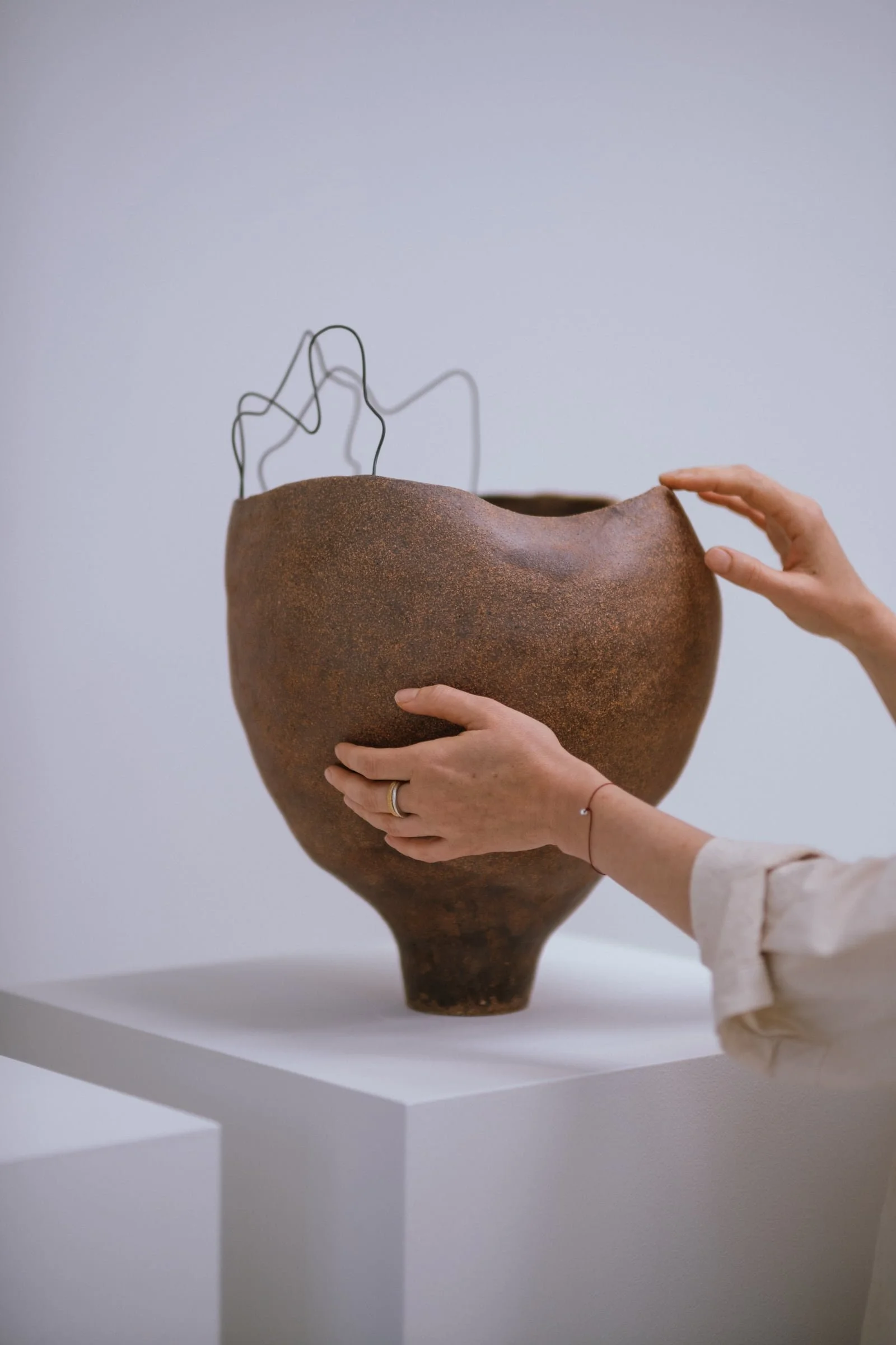 One-of-a-kind sculptural ceramic commission vase with wire detail by Anna Shipulina, photographed in a minimal interior setting.
