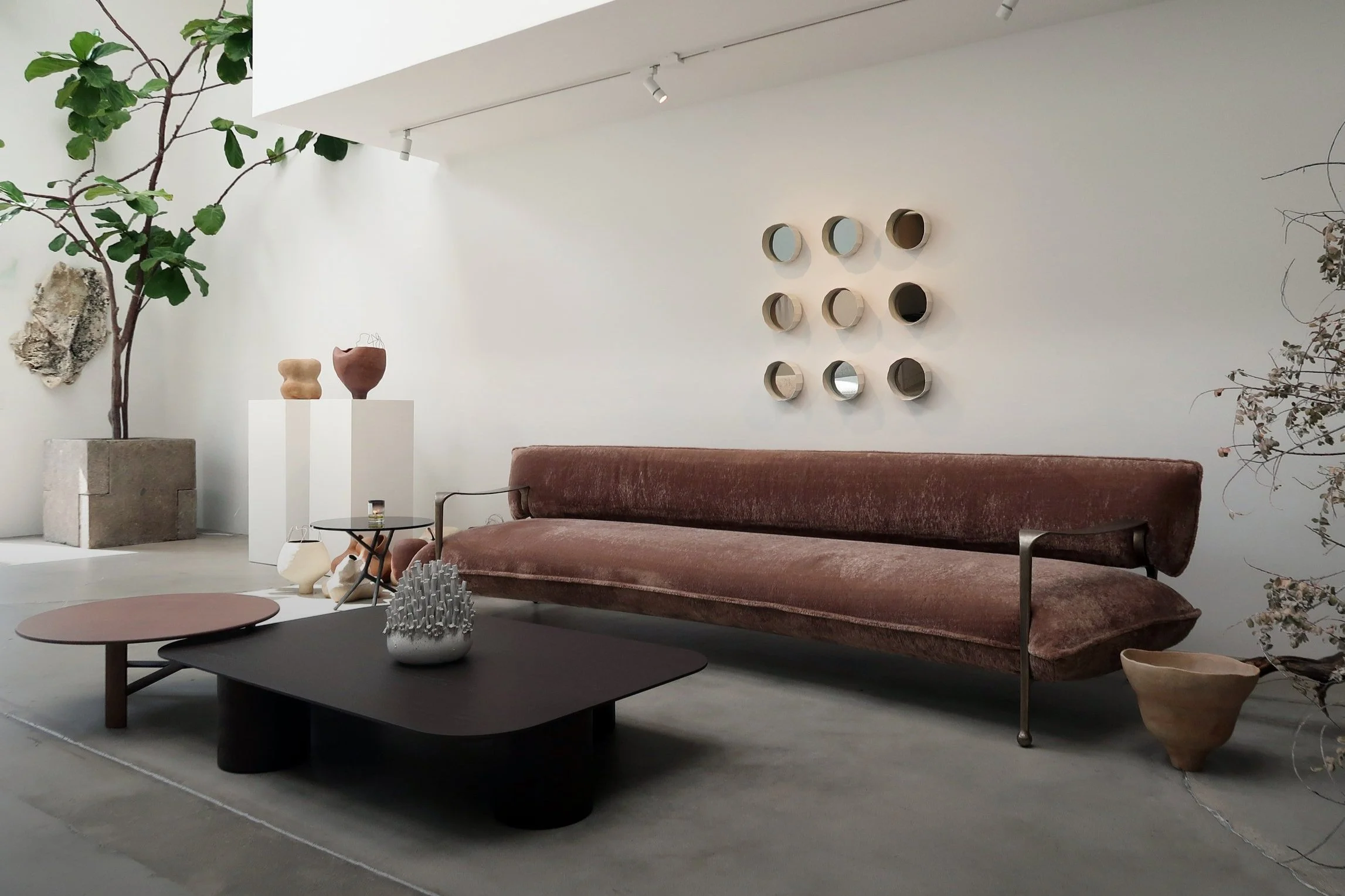 Handmade ceramic sculptures displayed in a contemporary interior with pedestal, sofa, and wall installation