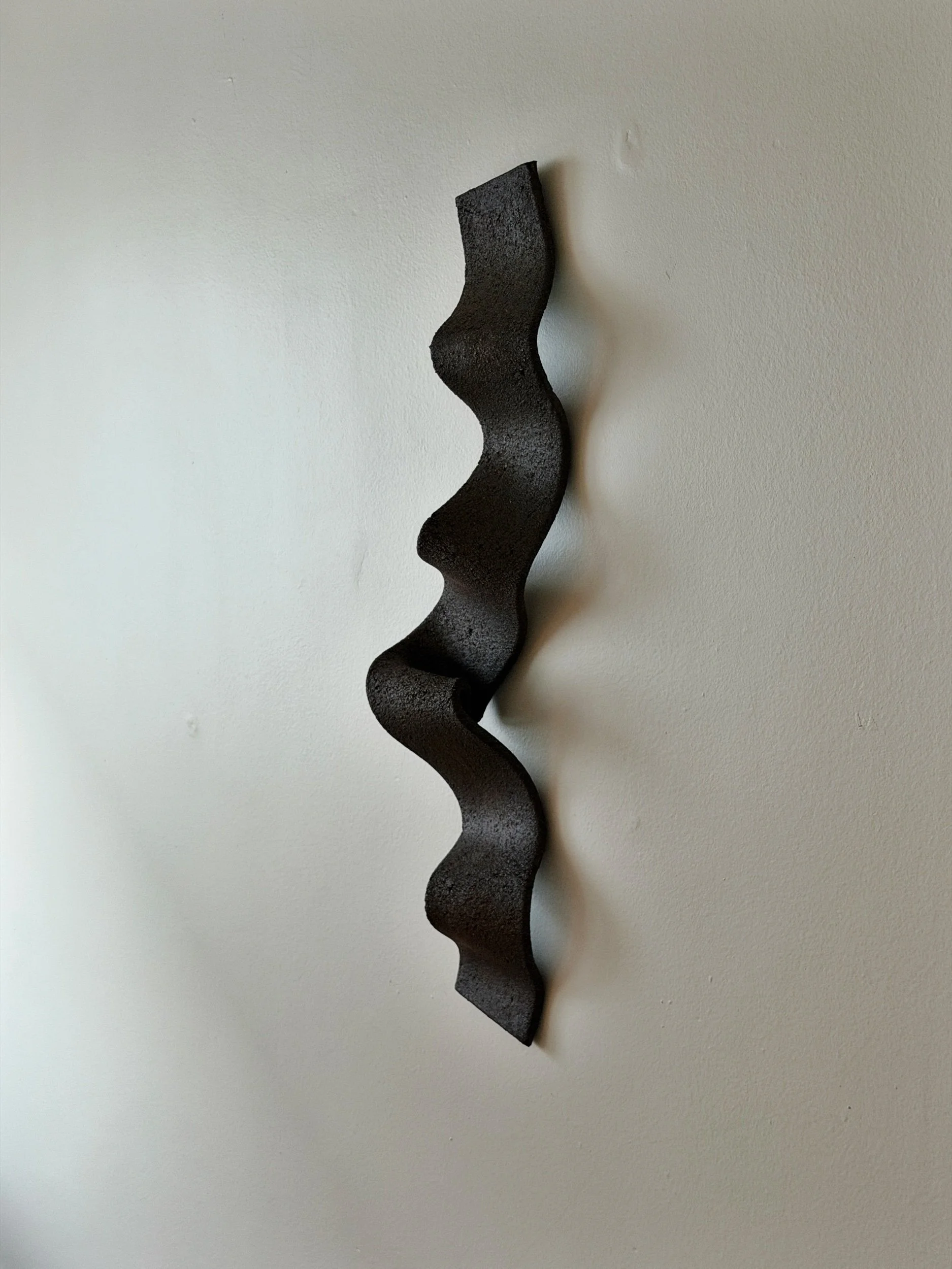 ceramic wall sculpture in black textured clay