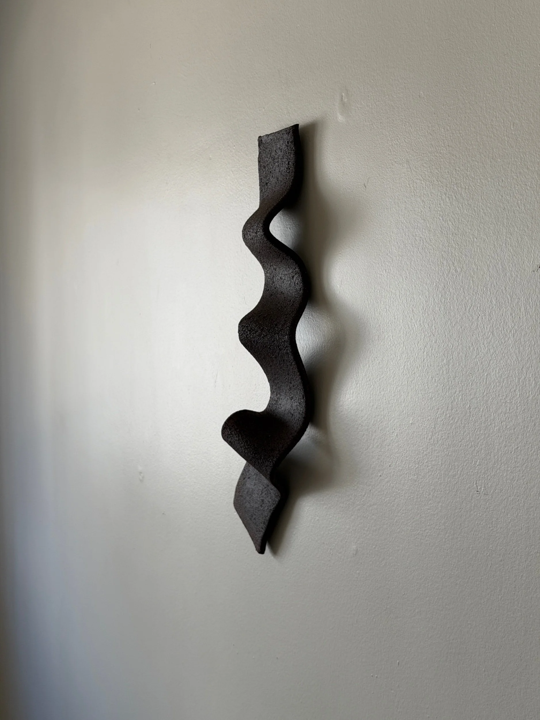 ceramic wall sculpture in a shape of the ribbon in black clay