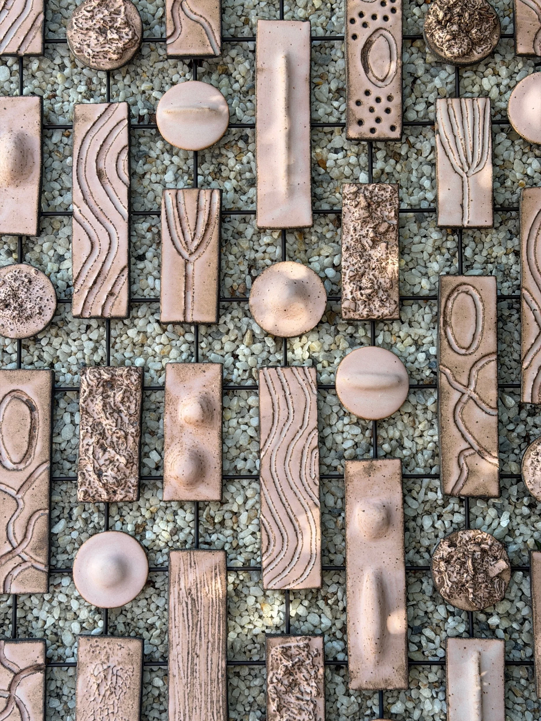 Ceramic tile wall installation by Anna Shipulina, Study II — hand-built blush-toned tiles with carved organic patterns and matte glazed surfaces, mounted on a metal grid.