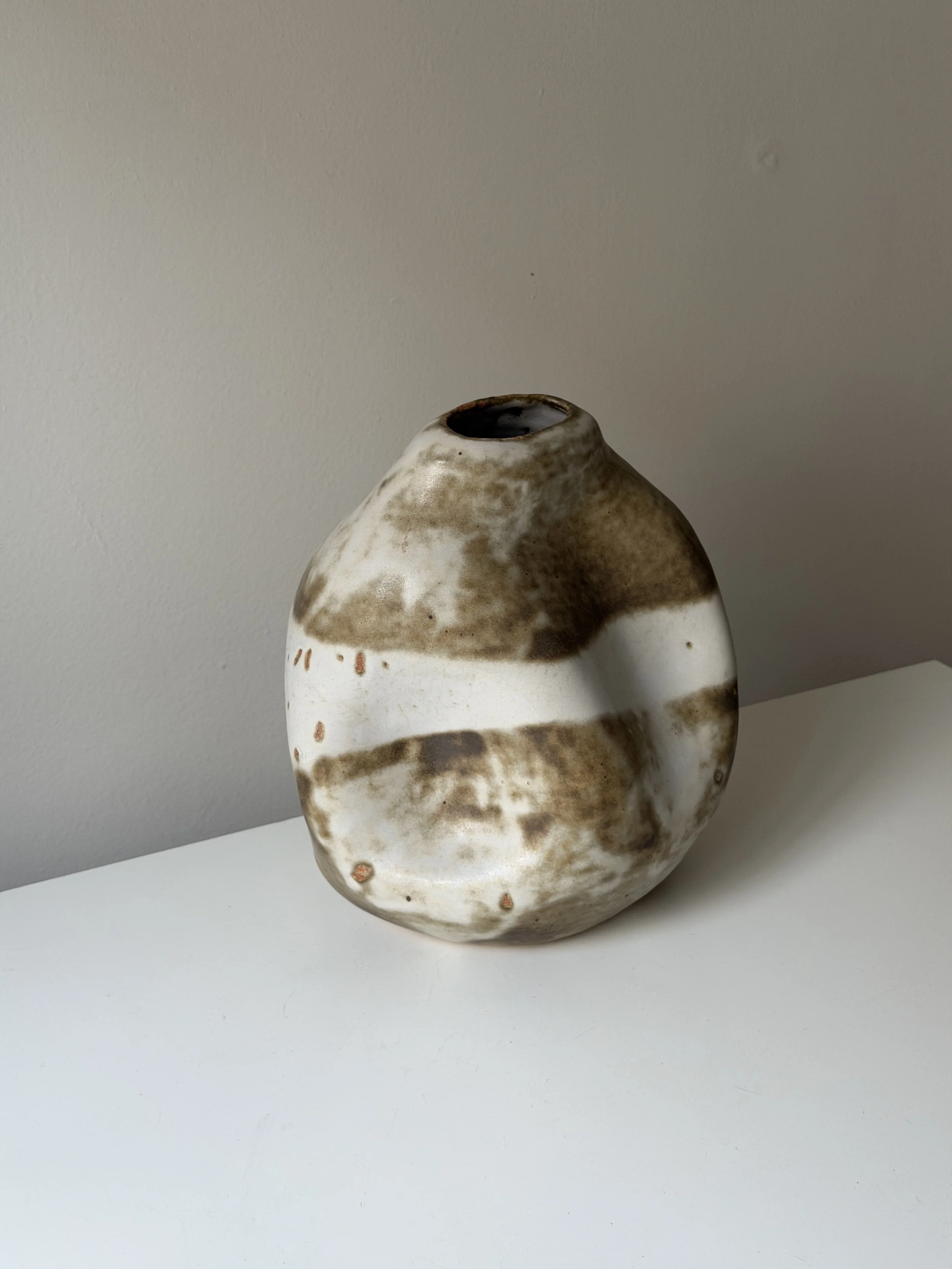 Handmade ceramic vase with an organic, sculptural silhouette and soft gray glazed surface.