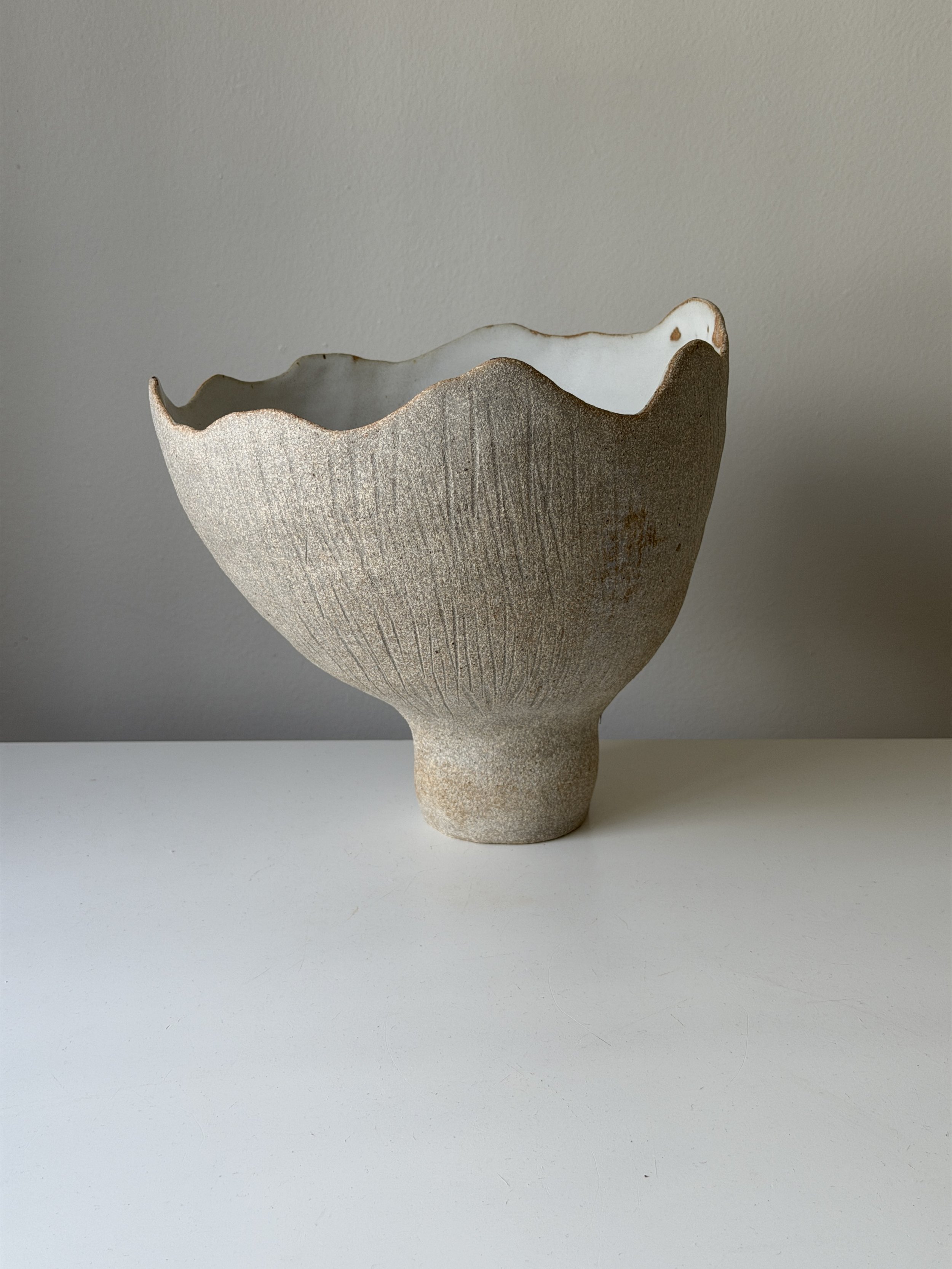 This handcrafted ceramic vase is shaped entirely by hand, creating a unique sculptural form with a raw, organic surface. Finished in natural clay tones