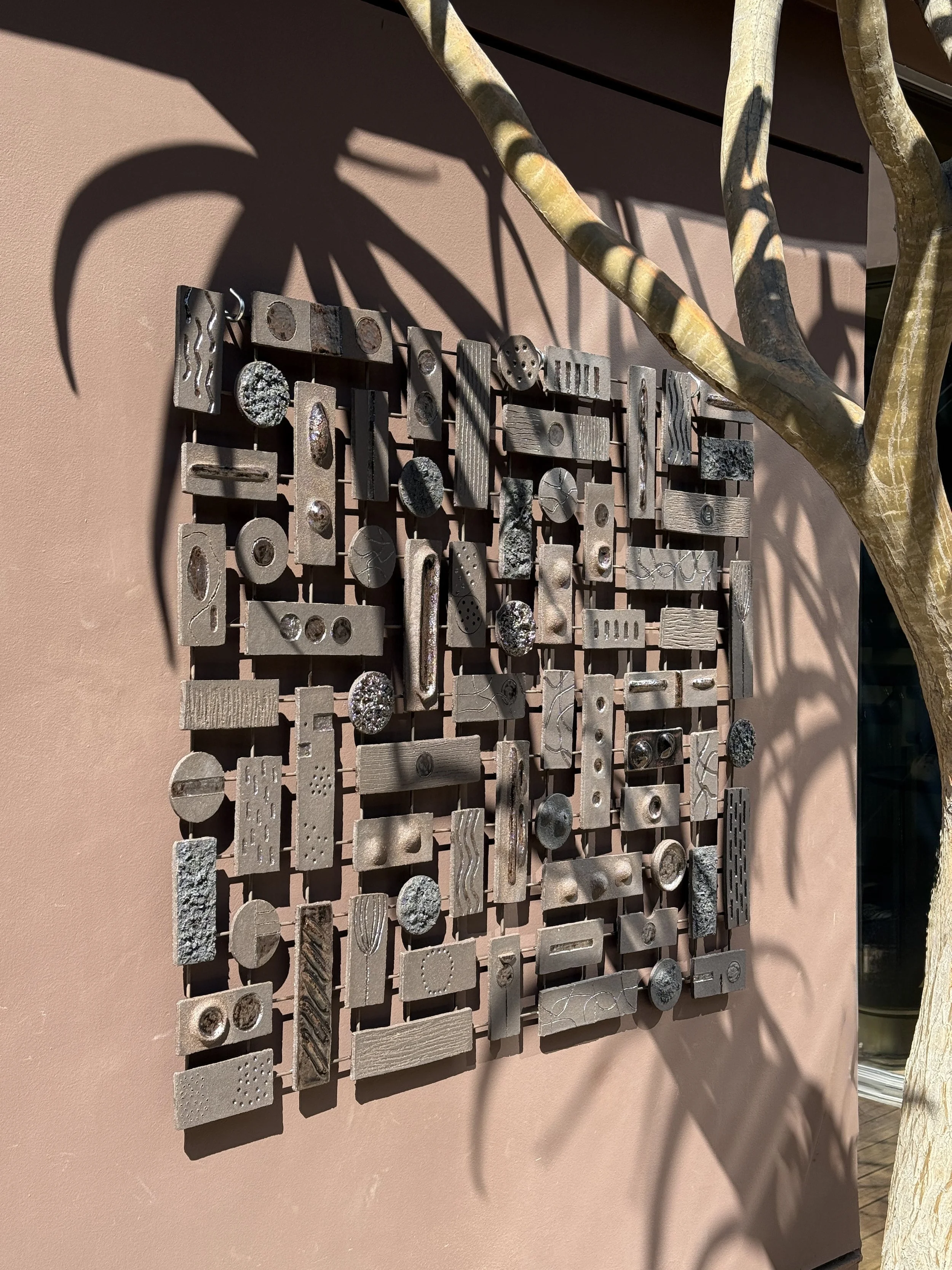 Modular ceramic wall sculpture installation made of textured clay tiles arranged in geometric composition