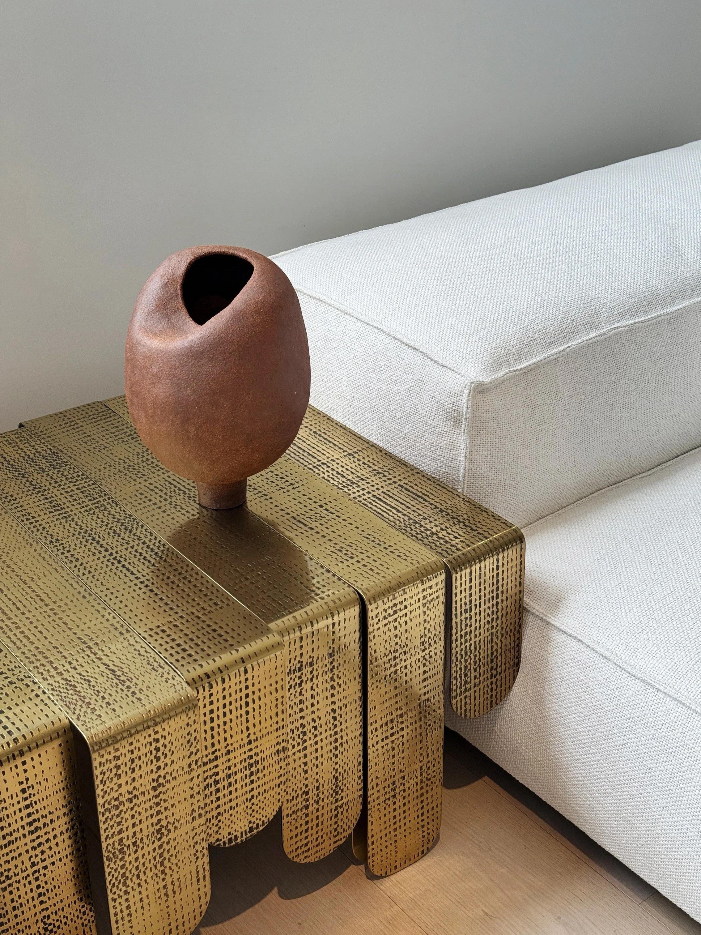 Sculptural terracotta ceramic vase, hand-built in stoneware, styled on a brass side table in a contemporary living room.