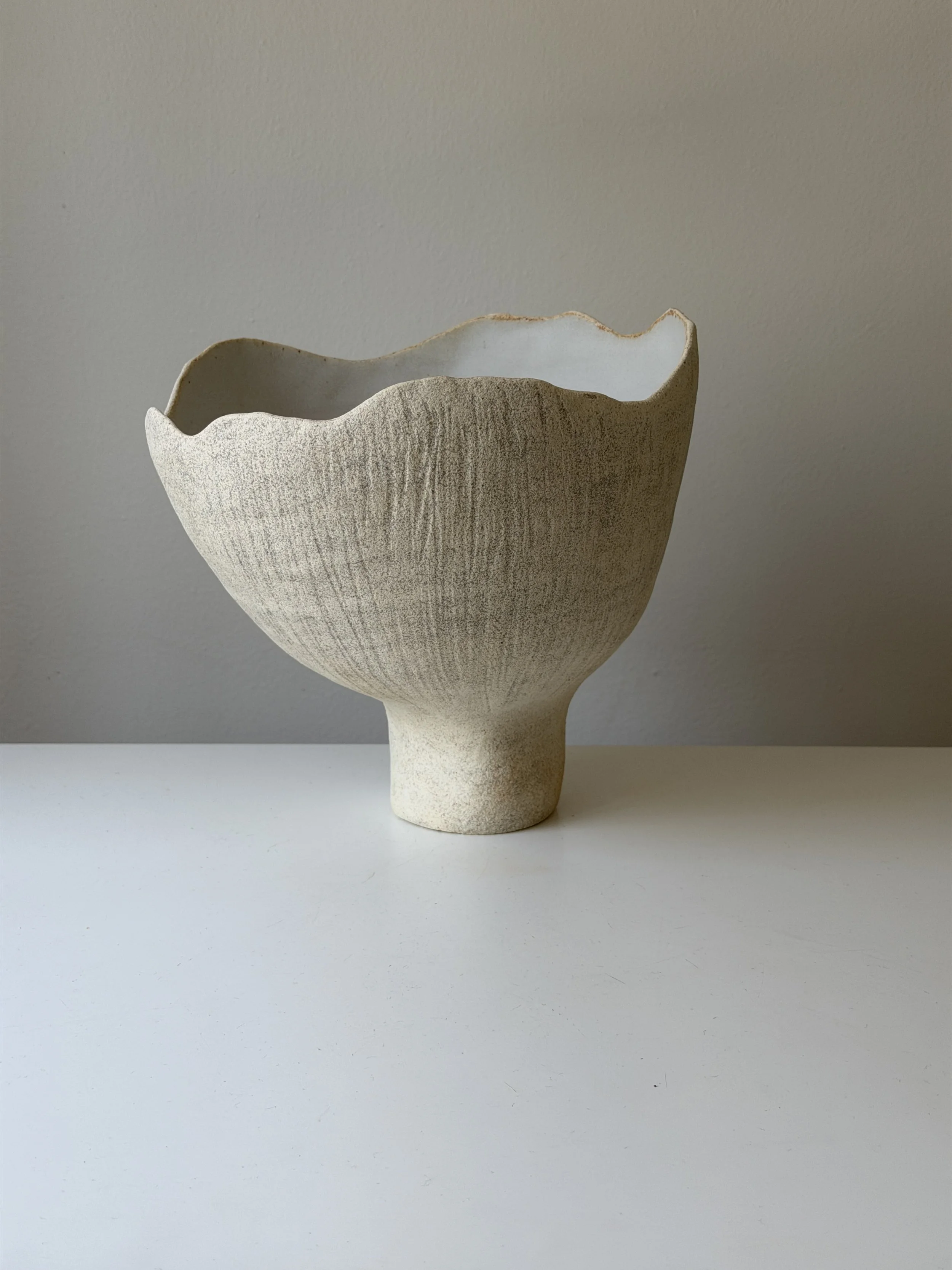 Handmade ceramic vase created using handbuilding techniques. This one-of-a-kind pottery piece features a textured surface and neutral color palette