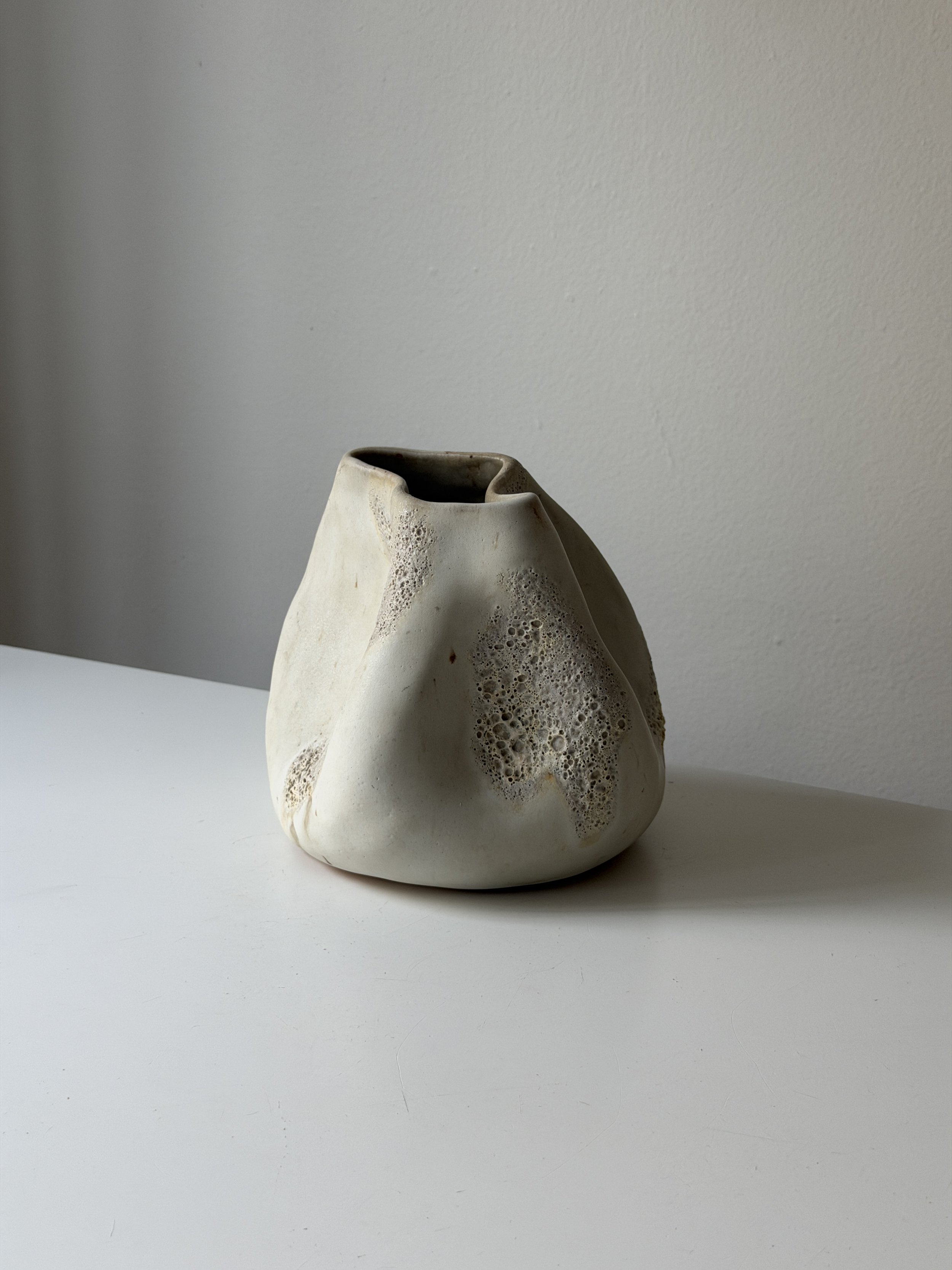 Off-white organically shaped ceramic vase with texture.