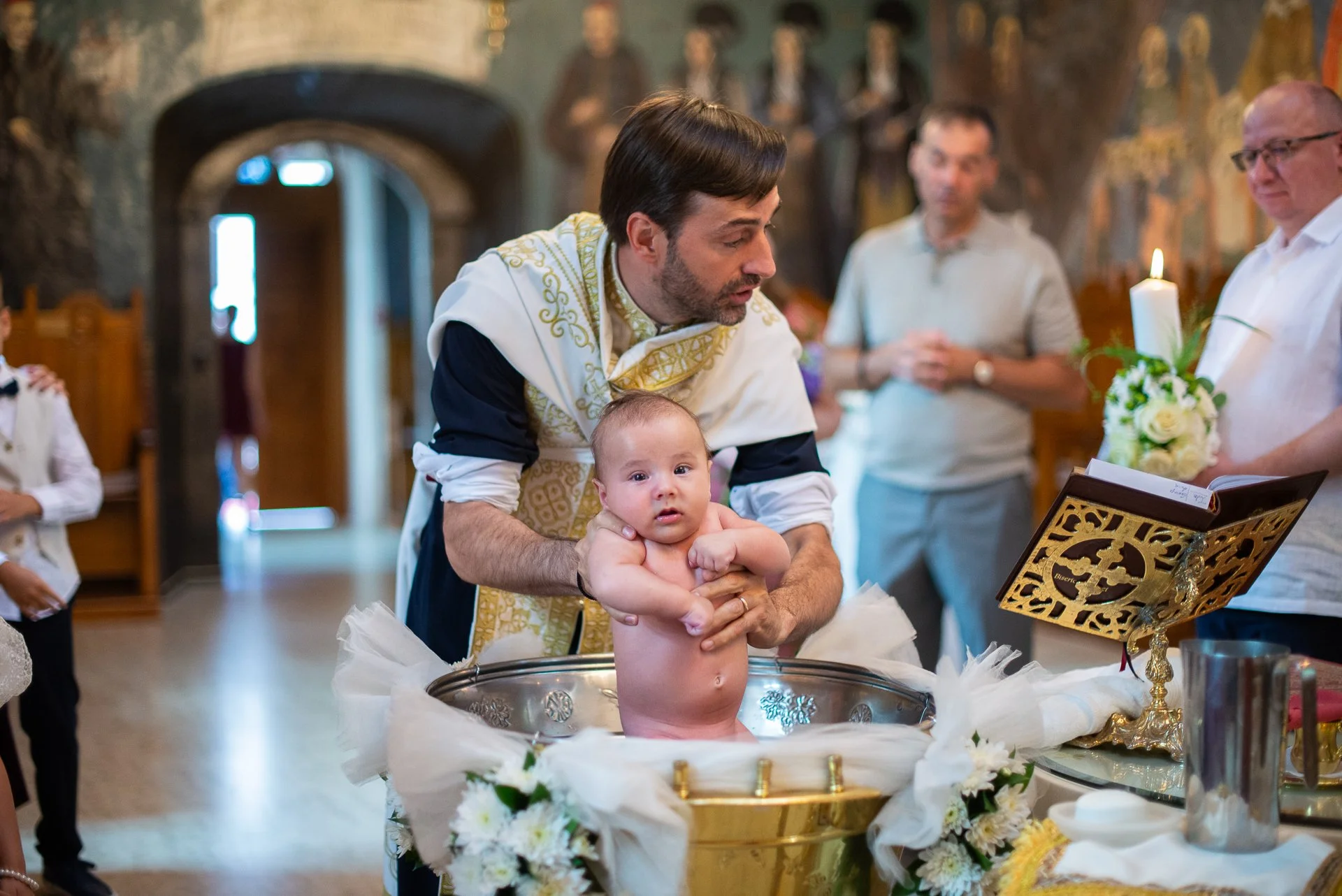 bebelus care se uita din cristelnita in aparatul foto