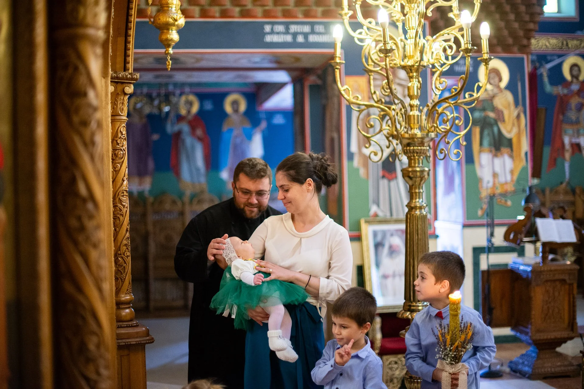 nasii impreuna cu copiilor tin in barte bebelusul botezat astfel incat sa fie impartasit