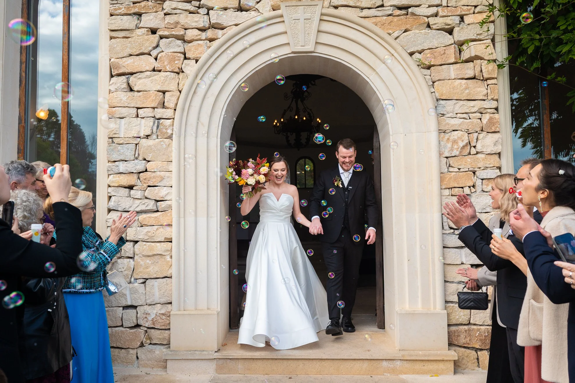 Ieșirea mirilor din biserică după cununia religioasă, surprinsă cu invitați și baloane de săpun, fotografie de nuntă.
