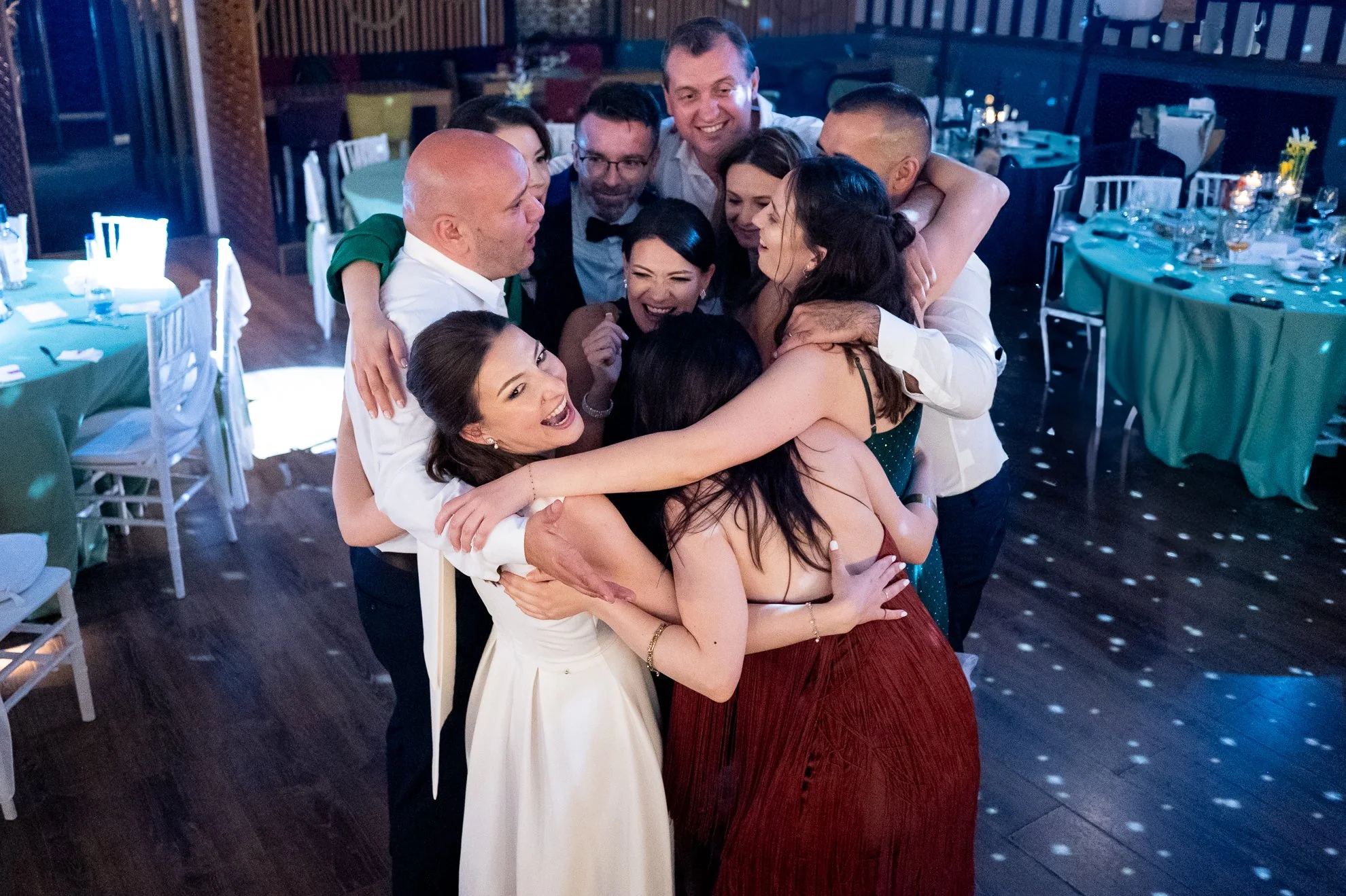 Moment de petrecere la nuntă, cu miri și prieteni îmbrățișați pe ringul de dans, fotografie de nuntă.