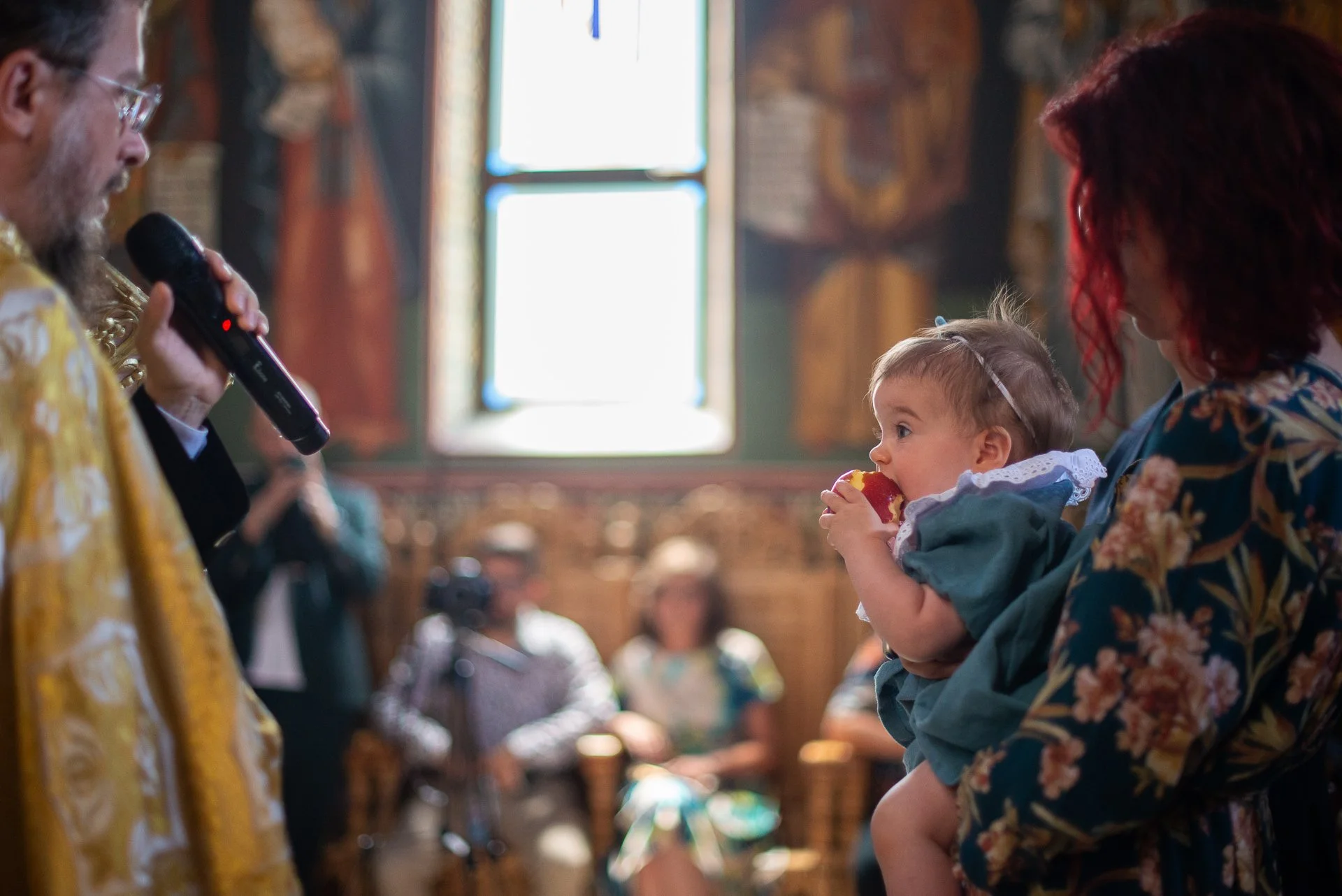 fetita musca din mar in brate la nasa in timpul slujbei de botez