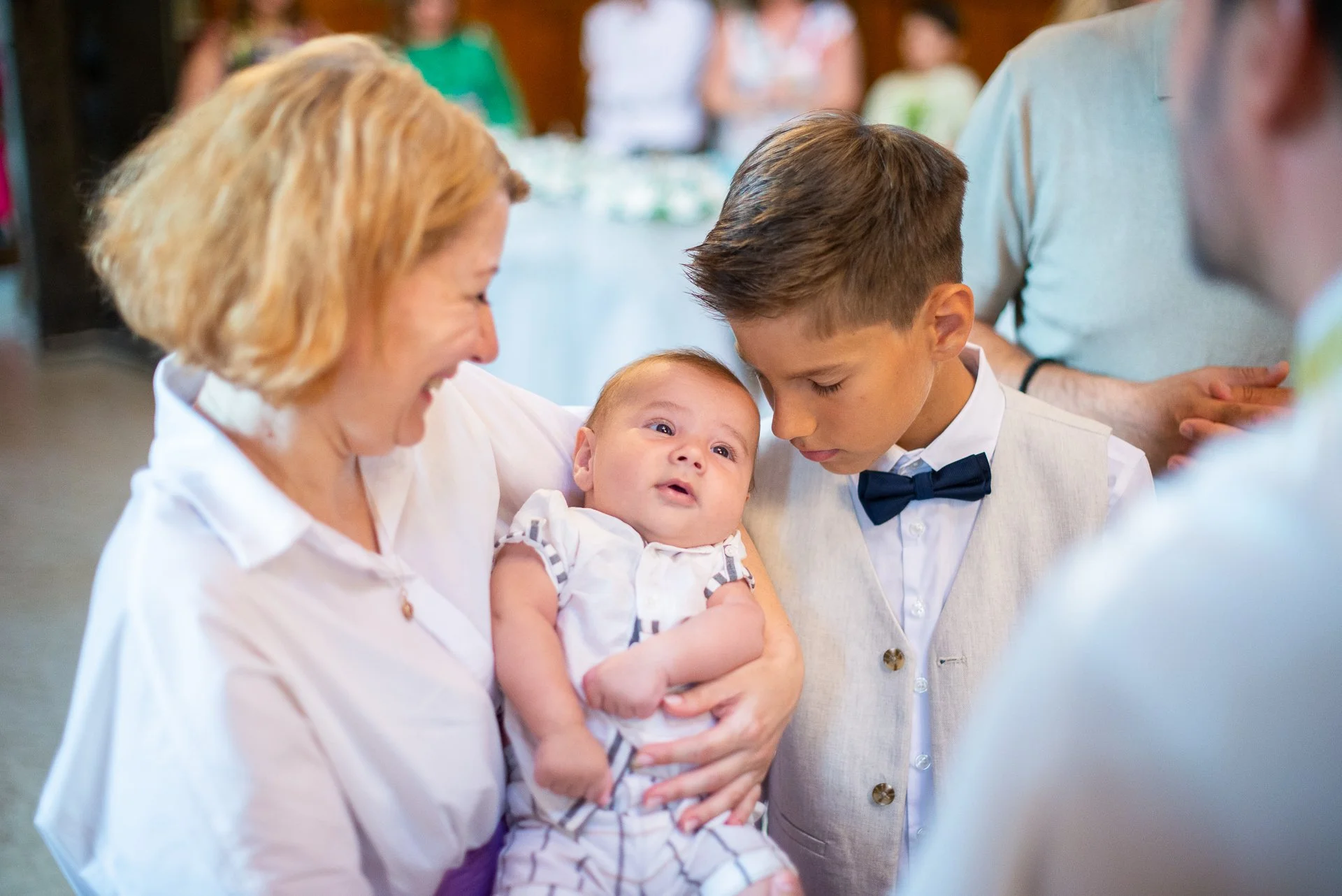 fratele mai mare al bebelusului botezat sta cu capul langa bebe si cu ochii inchisi