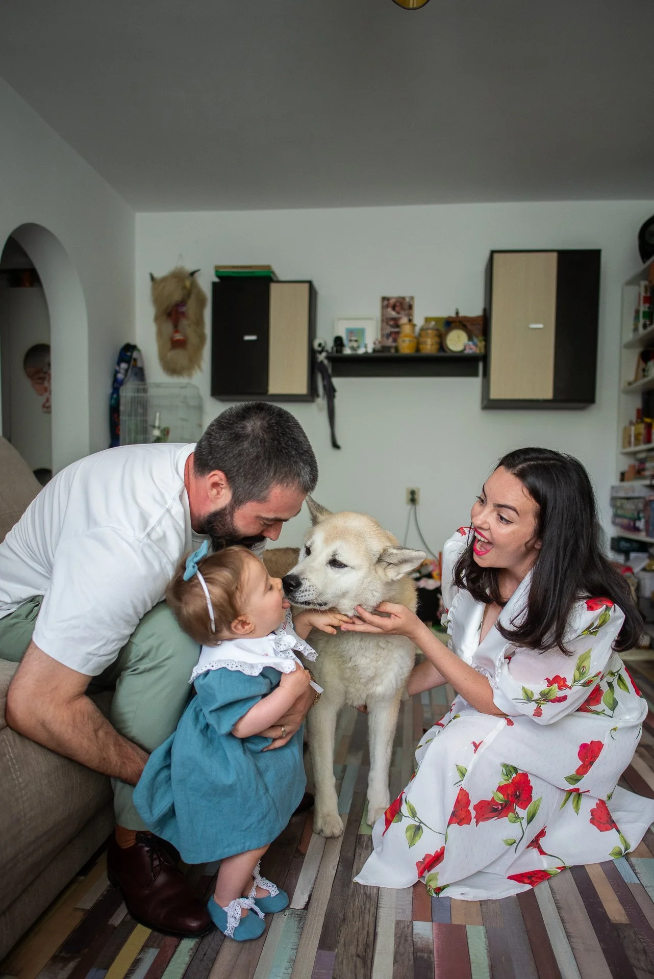 un catel linge pe fata o fetita care este inconjurata de mama si tata