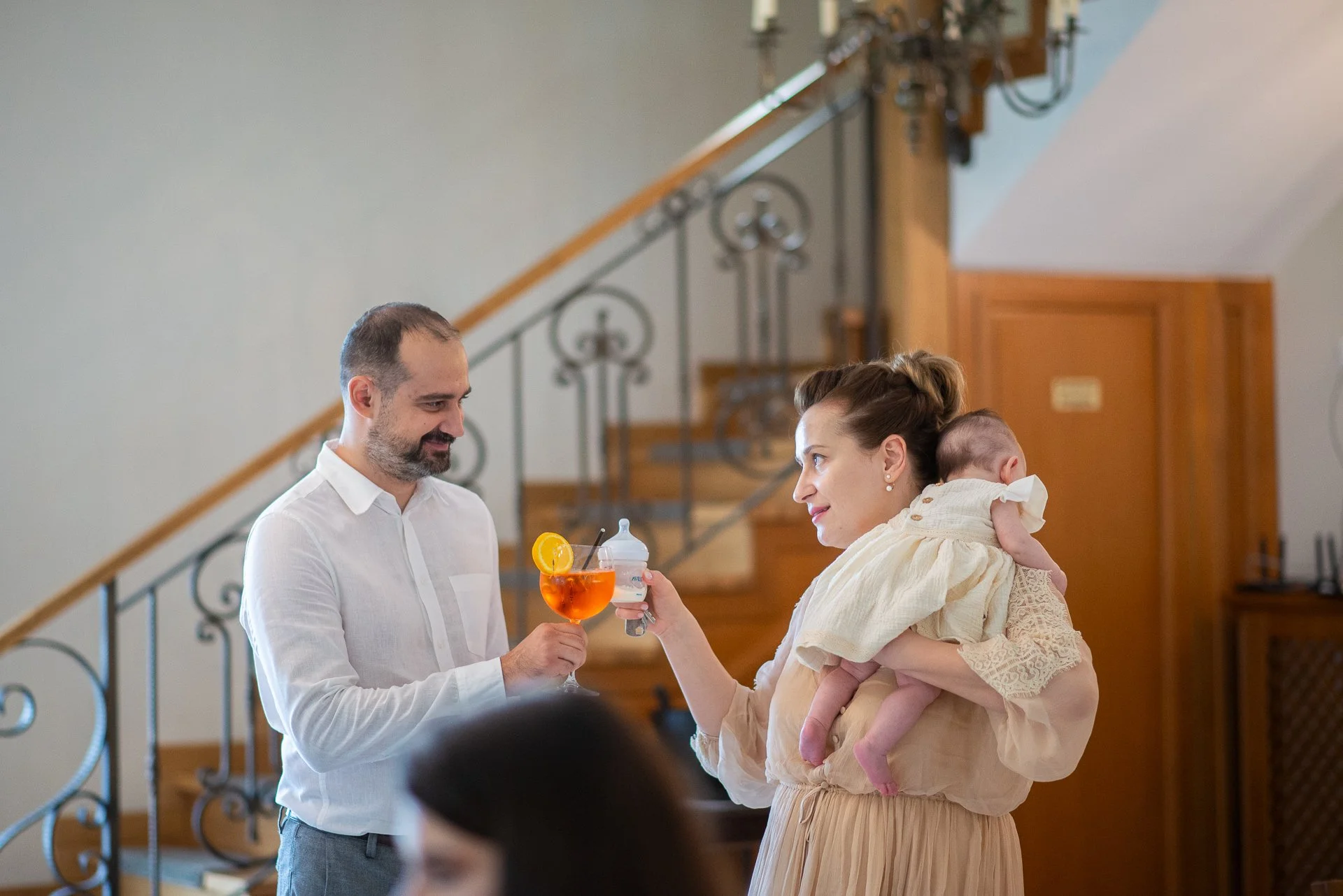 tata si mama bebelusului ciocnesc un pahar de bautura cu unul de lapte